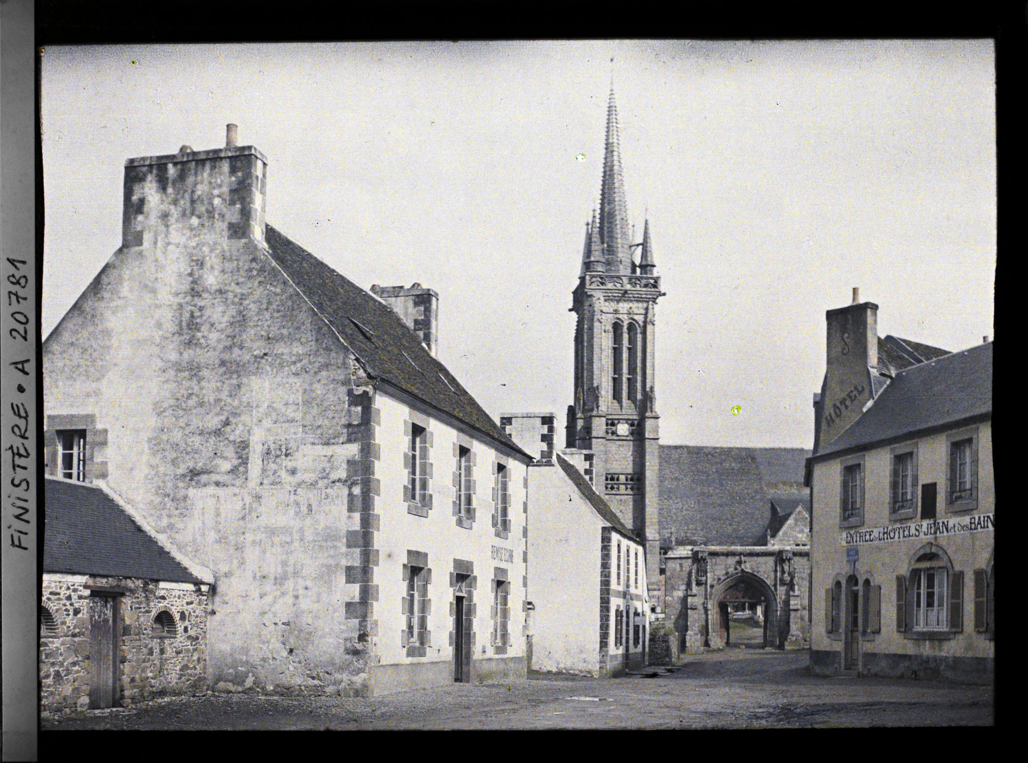 Image représentant Une place du village et l'église Saint-Jean-du-Doigt derrière la porte monumentale du cimetière