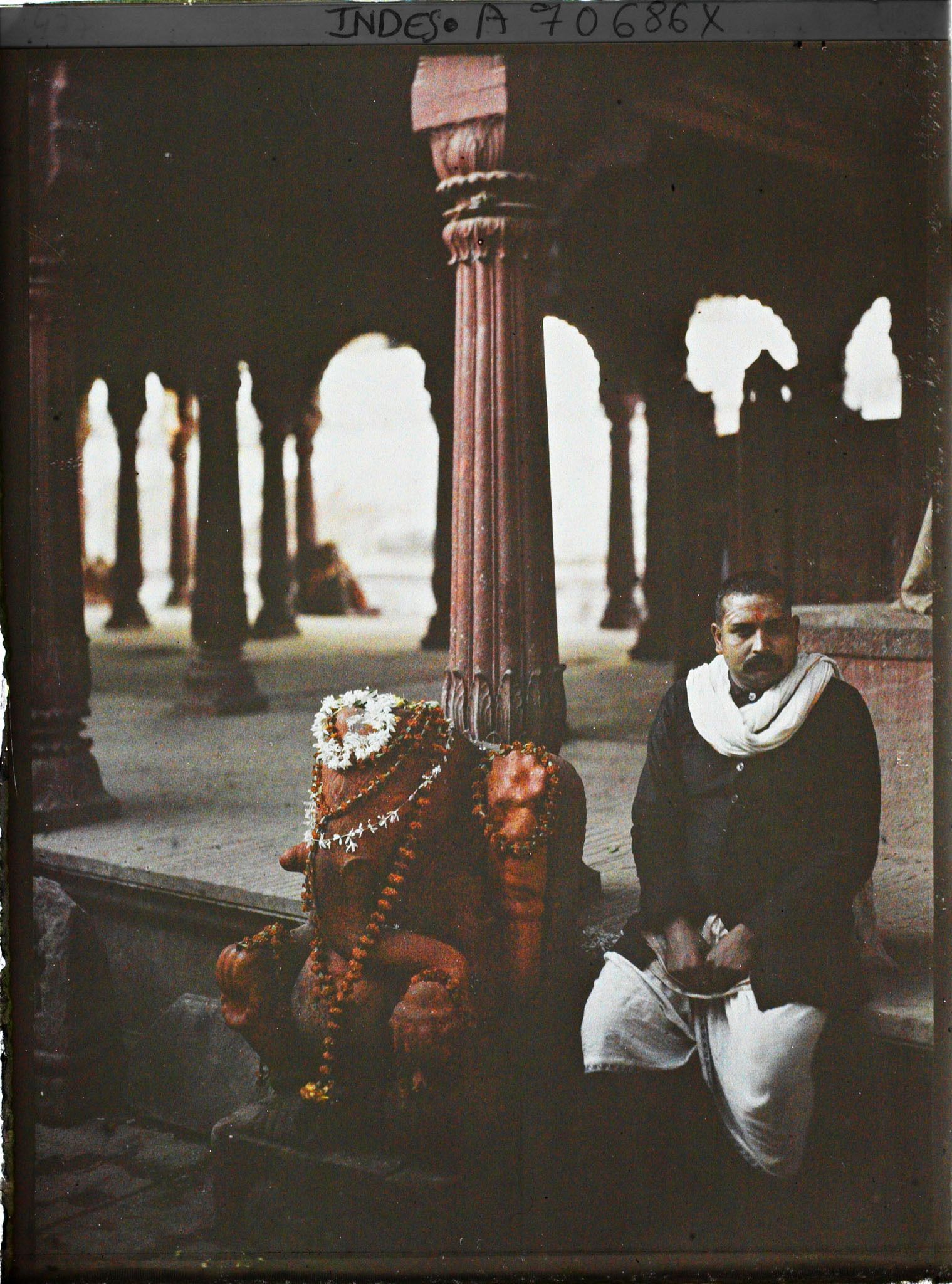 Image représentant Fidèle près de la statue de Ganesh couverte d'offrandes dans le temple de Vishvesvara