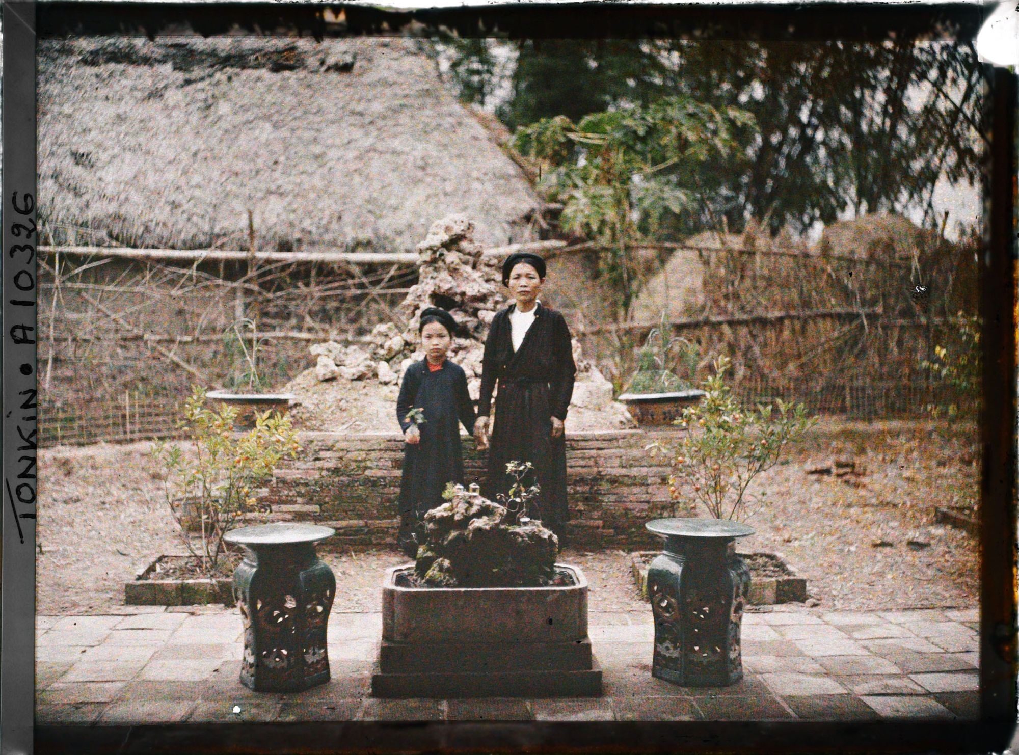 Image représentant Une mère et sa fille debout, dans la cour intérieure d'une habitation de notable