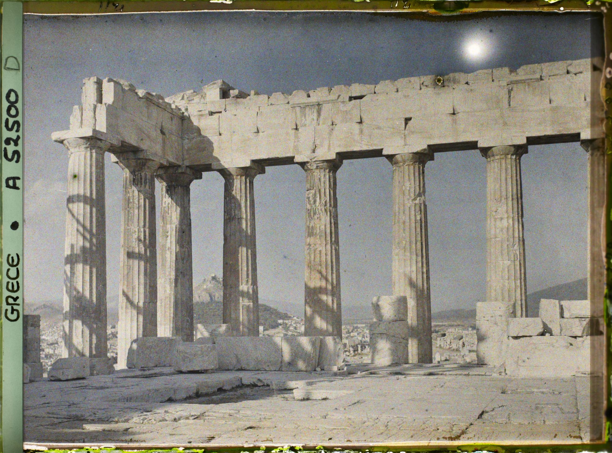 Image représentant Sur l'Acropole, le Parthénon. Vestiges de la colonnade extérieure côté est et derrière eux, la ville et le mont Lycabette