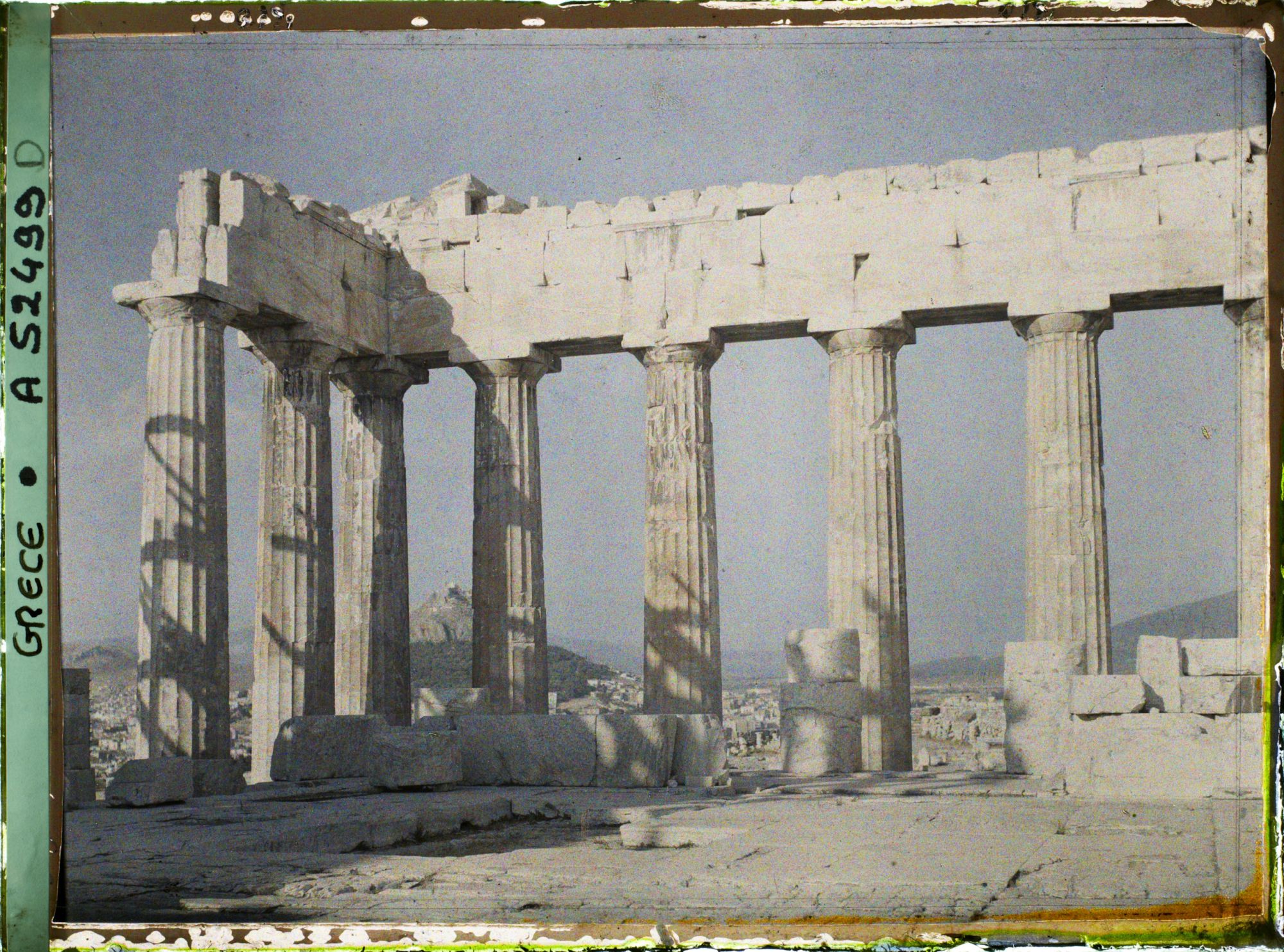 Image représentant Sur l'Acropole, le Parthénon. Vestiges de la colonnade extérieure côté est et derrière eux, la ville et le mont Lycabette