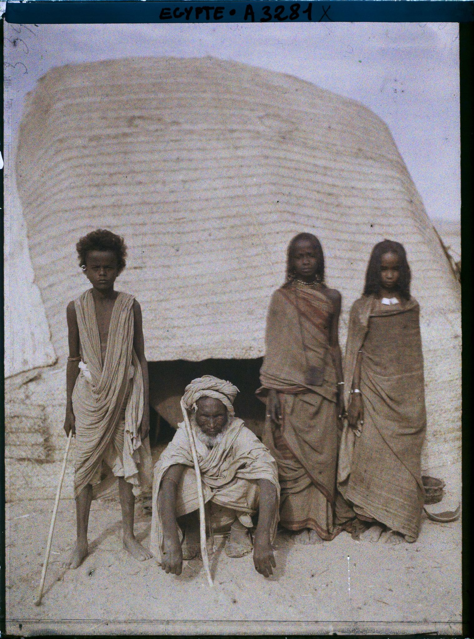 Image représentant Trois enfants et un vieillard  null bishari posent pour l'opérateur devant l'entrée d'une habitation