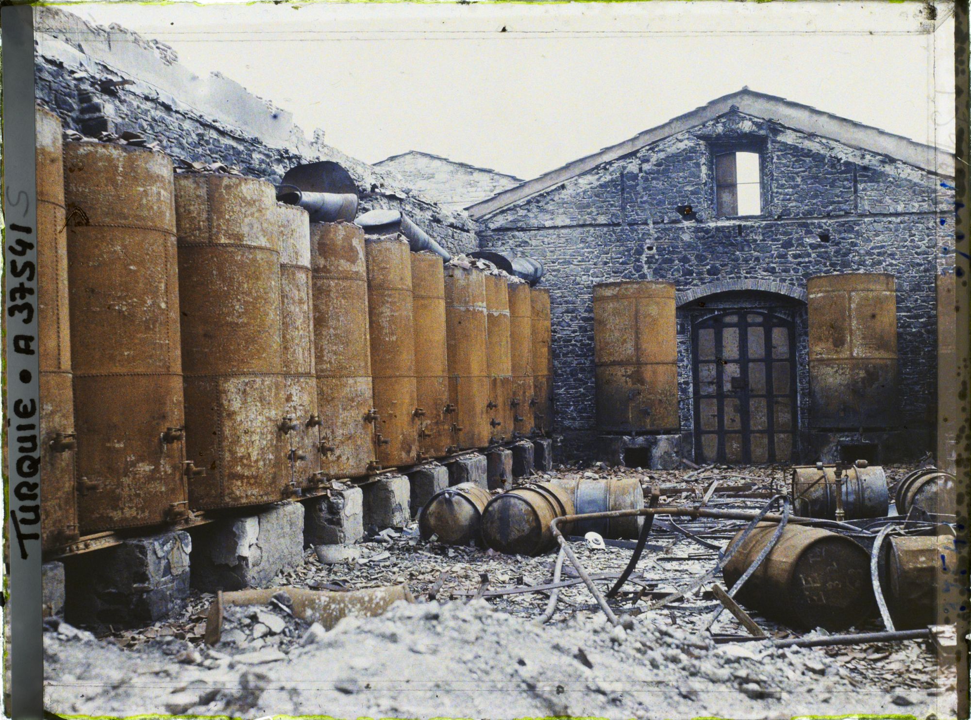 Image représentant Série de réservoirs dans la cour d'une huilerie en ruines (rue parallèle)