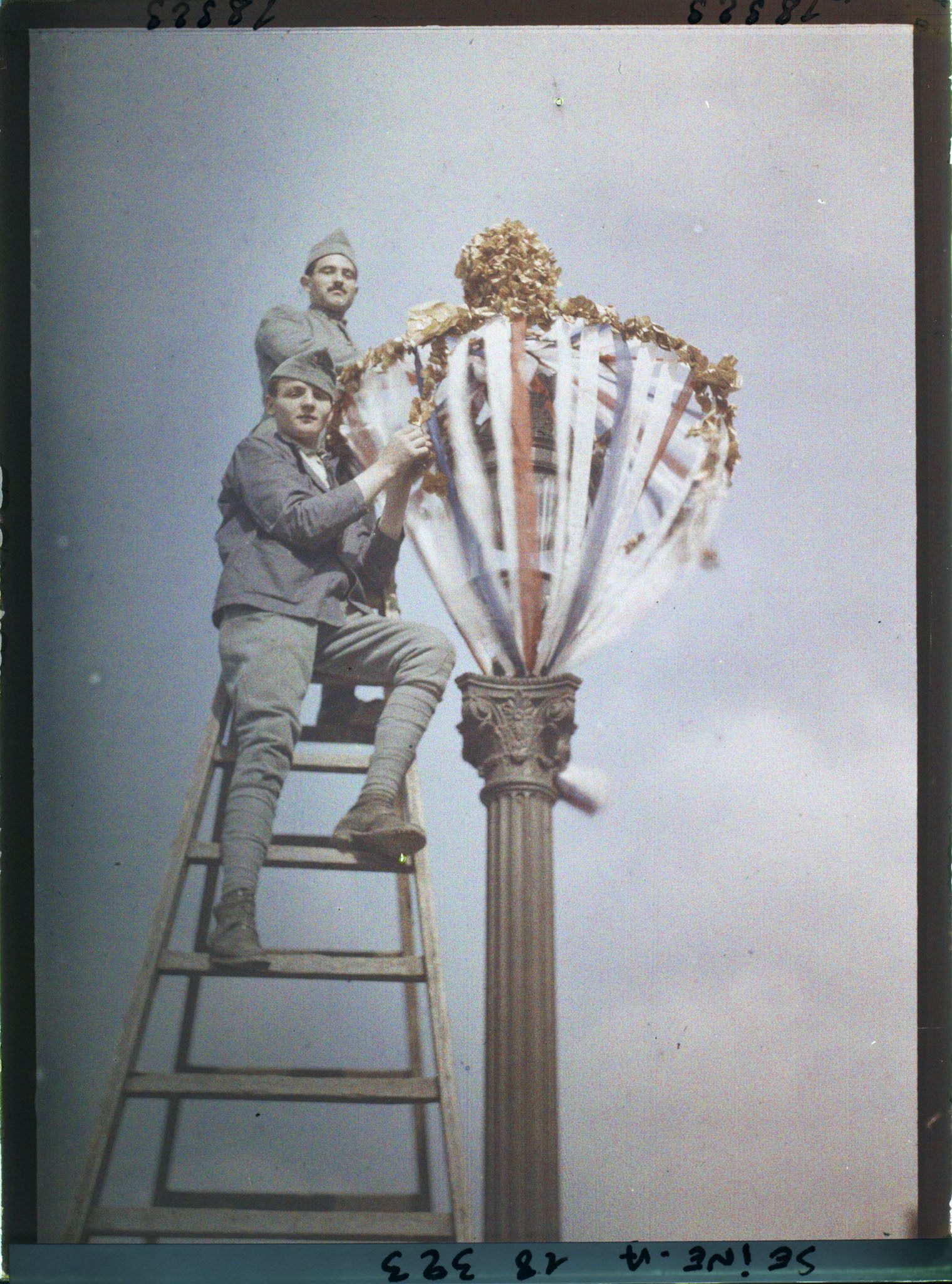 Image représentant Deux soldats décorant un lampadaire pour les fêtes de la Victoire des 13 et 14 juillet 1919