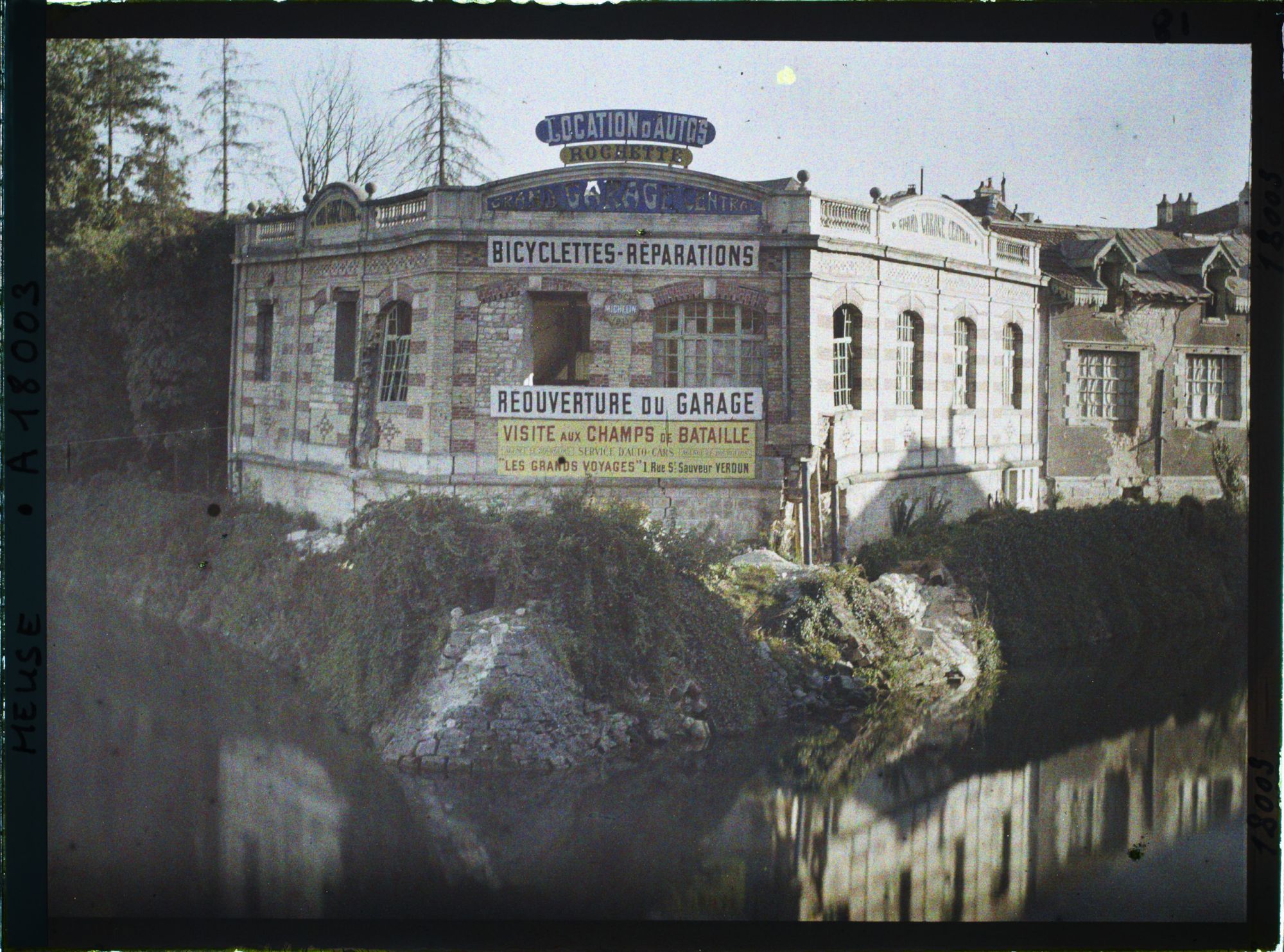 Image représentant France, Verdun, Un garage d'automobiles s/ les bords de la Meuse : On lit l'affiche des Voyges s/ le front.
