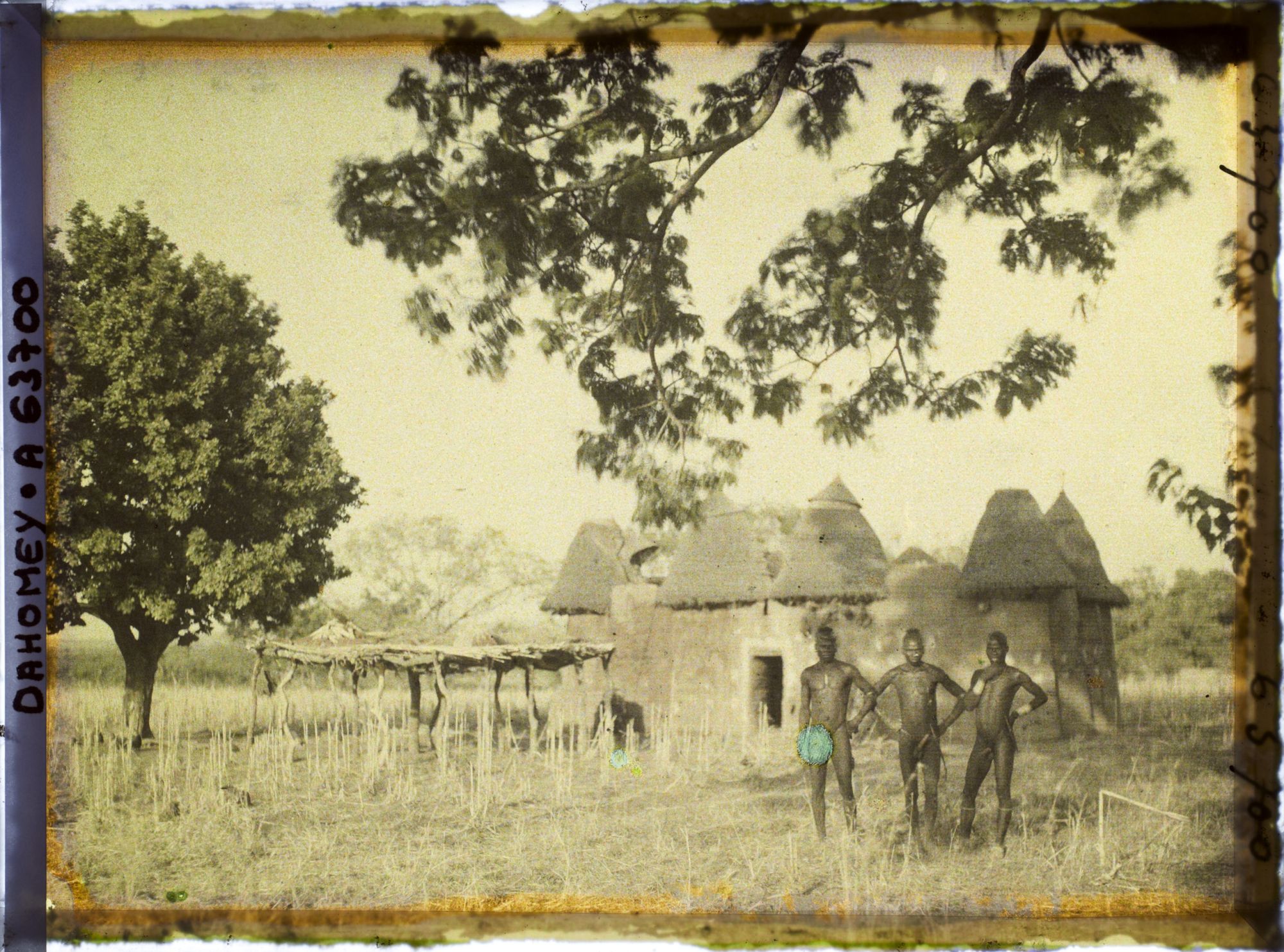 Image représentant Trois hommes somba devant un tata (case) et une plate-forme à sécher le mil