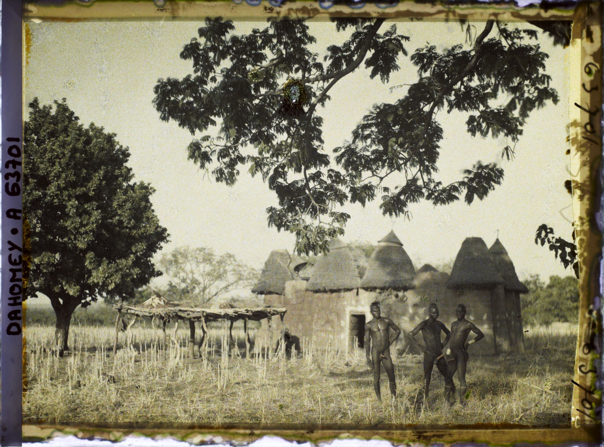 Image représentant Trois hommes somba devant un tata (case) et une plate-forme à sécher le mil