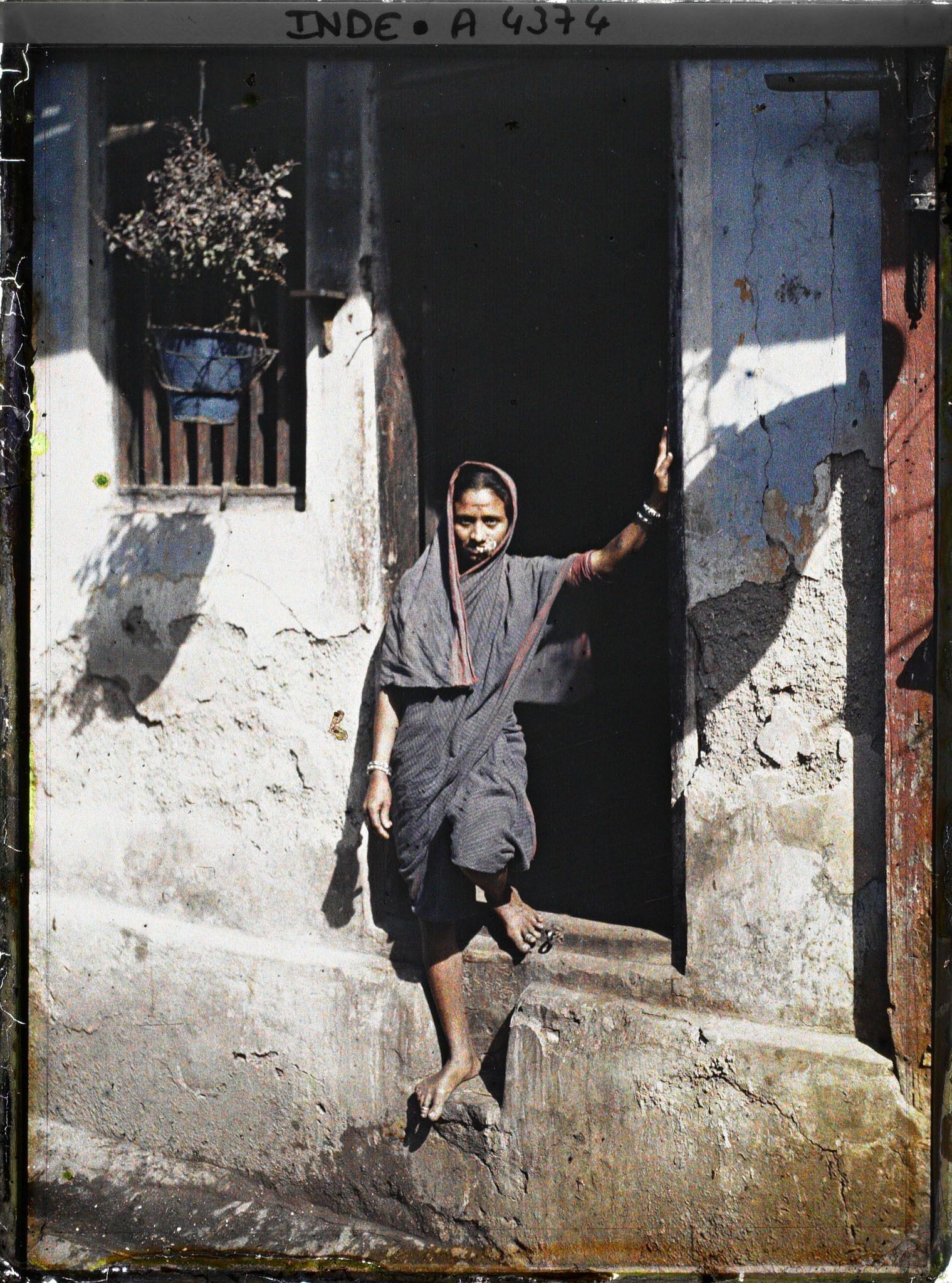 Image représentant Femme au sari drapé en dhoti court, sur le pas de sa porte