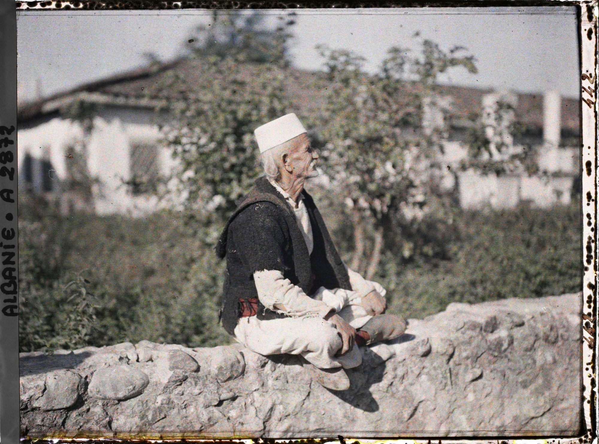 Image représentant Vieil homme sur le muret d'un cimetière