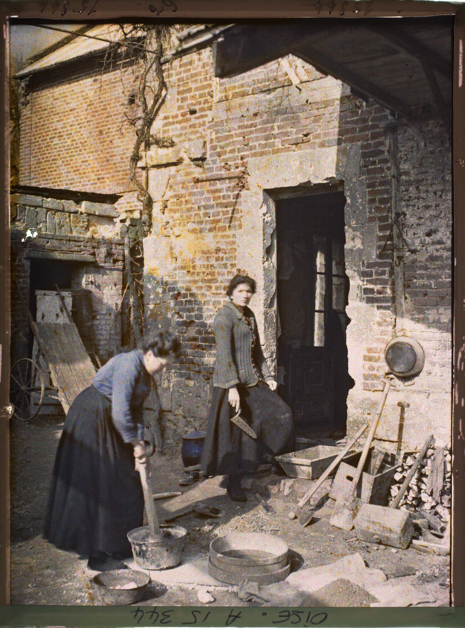 Image représentant France, Elincourt Ste Marguerite, Guerre Mme Censier pilant de la pierre de Chaux. Pour réparer sa Maison