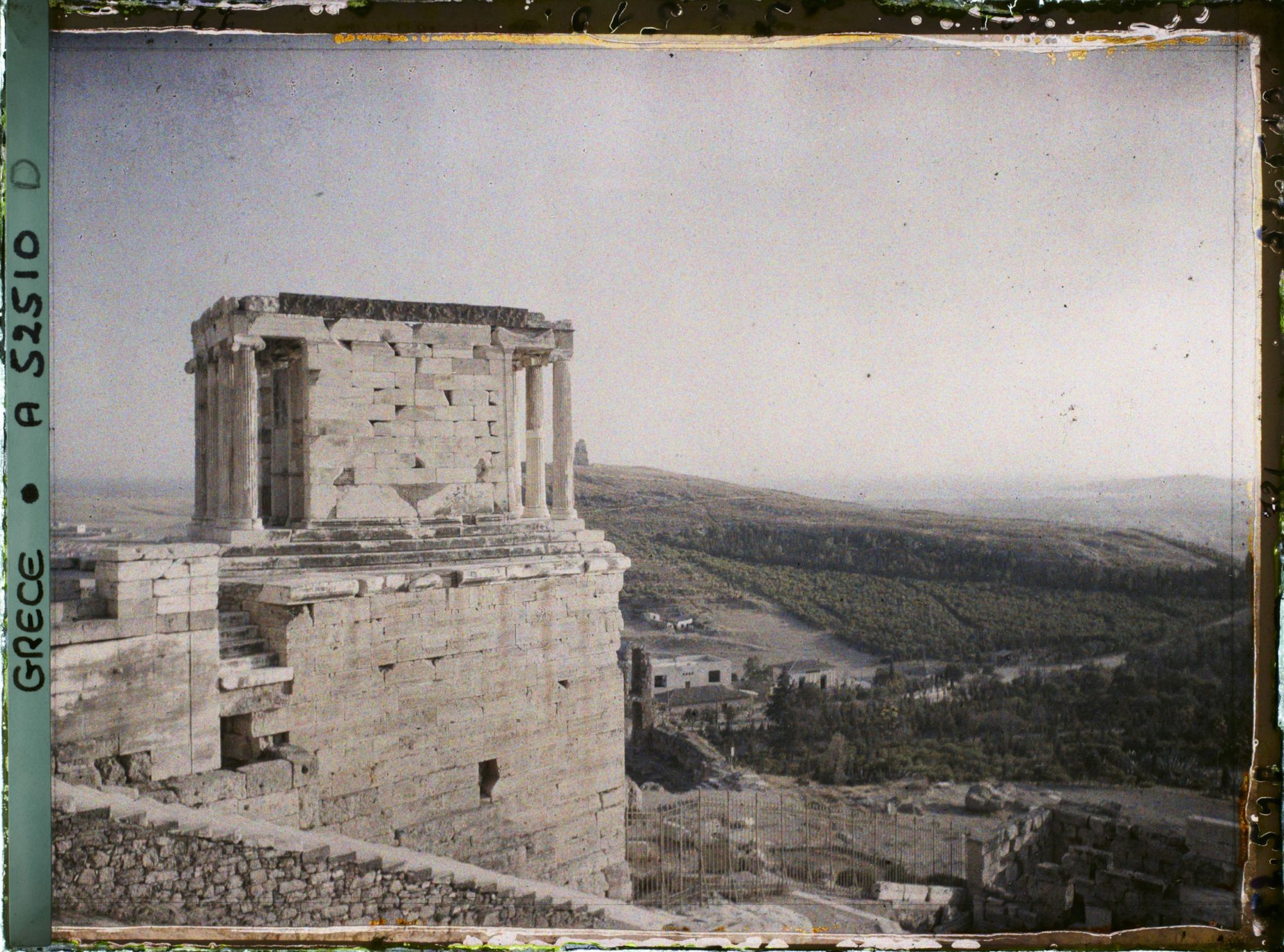Image représentant L'extrémité ouest de l'Acropole et les escaliers y menant au premier plan, et le Temple d'Athéna Nike (profil nord)