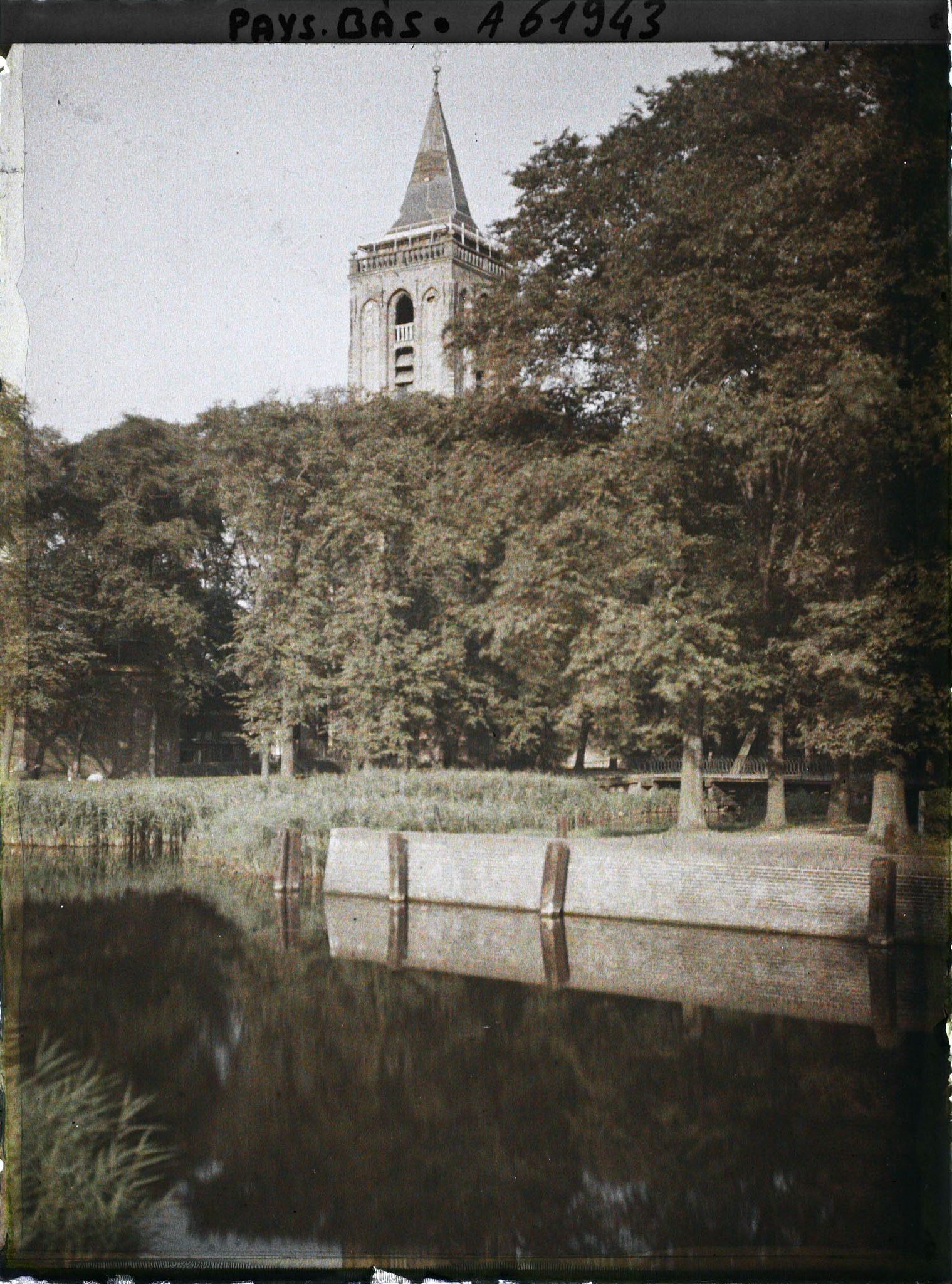 Image représentant L'étang situé près de l'église, à l'arrière plan le clocher