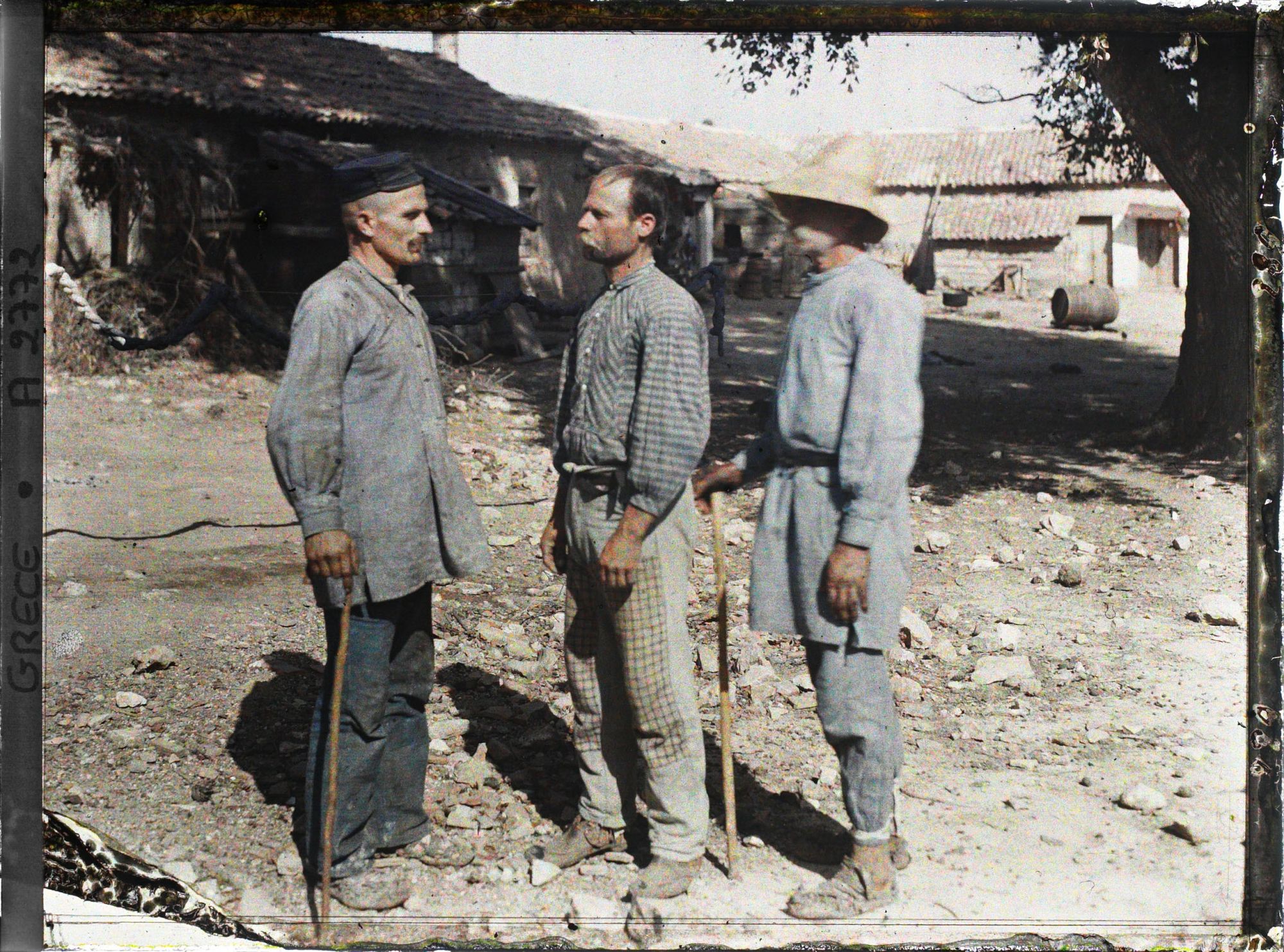 Image représentant Trois paysans (d'origine albanaise) - de profil - dans une cour de ferme