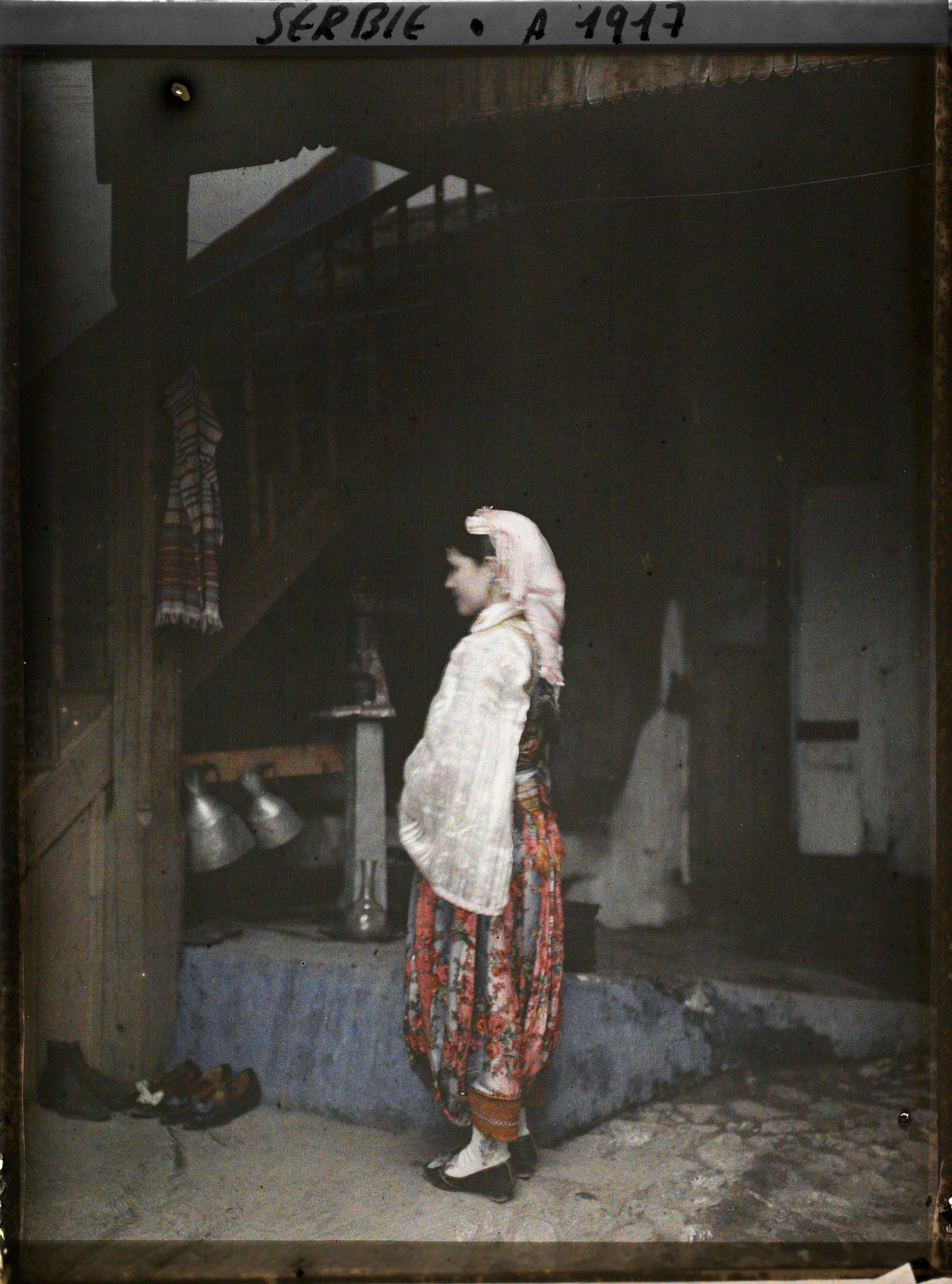 Image représentant Une fillette serbe en costume traditionnel dans la cour d'une maison