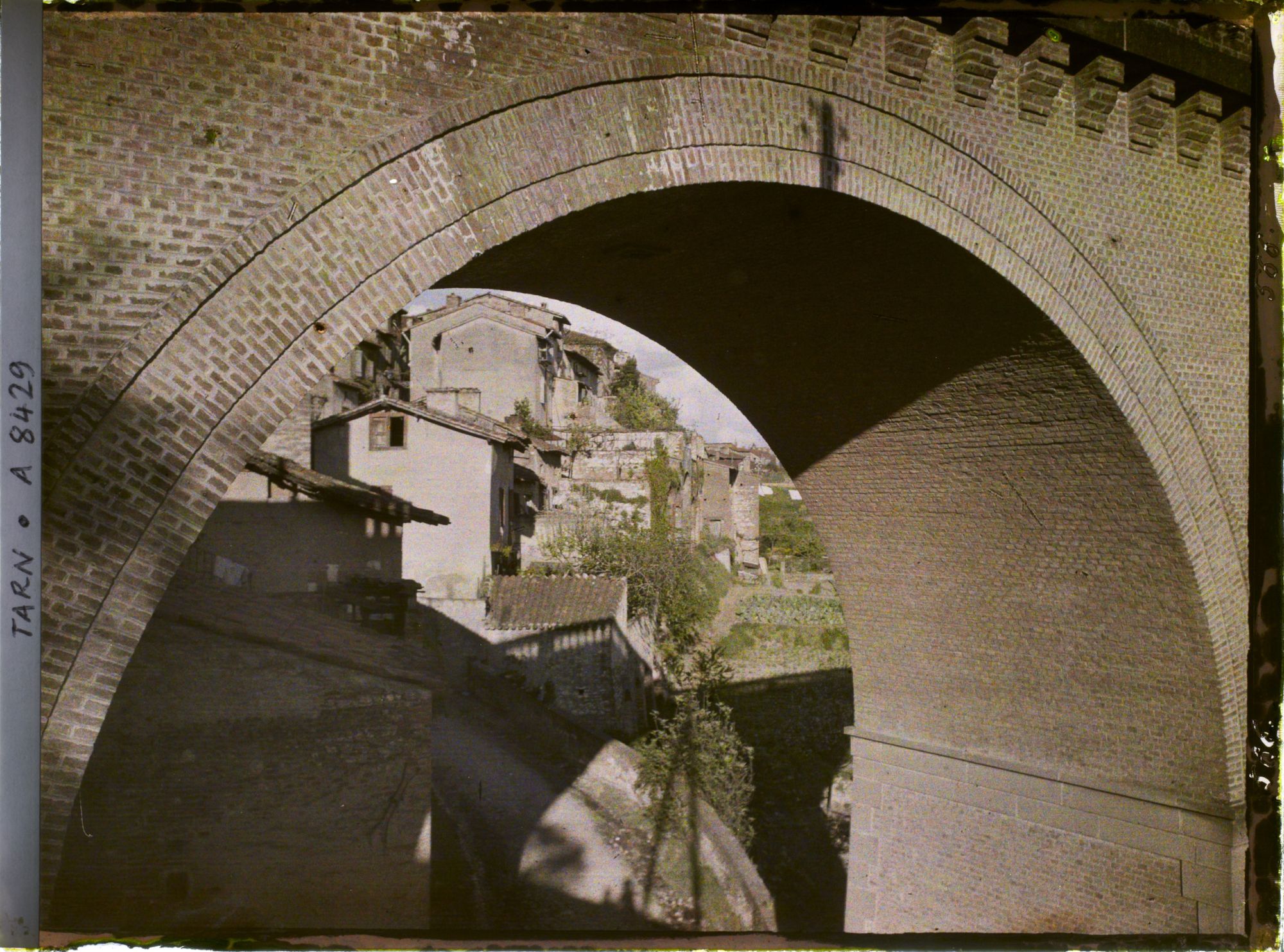 Image représentant Vue des maisons prise depuis une arche du pont de chemin de fer