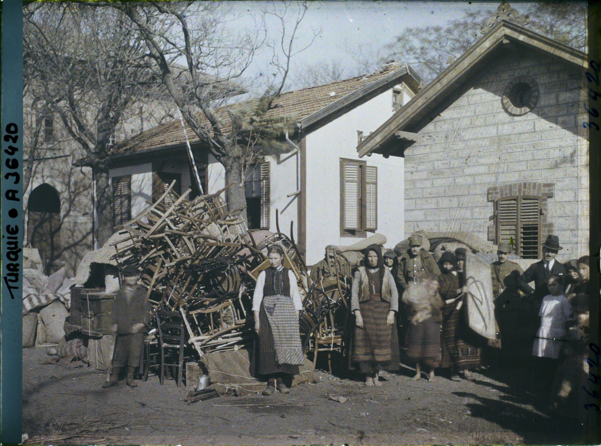 Image représentant Grecs quittant la ville près d'un amas de mobiliers, aux abords de la gare