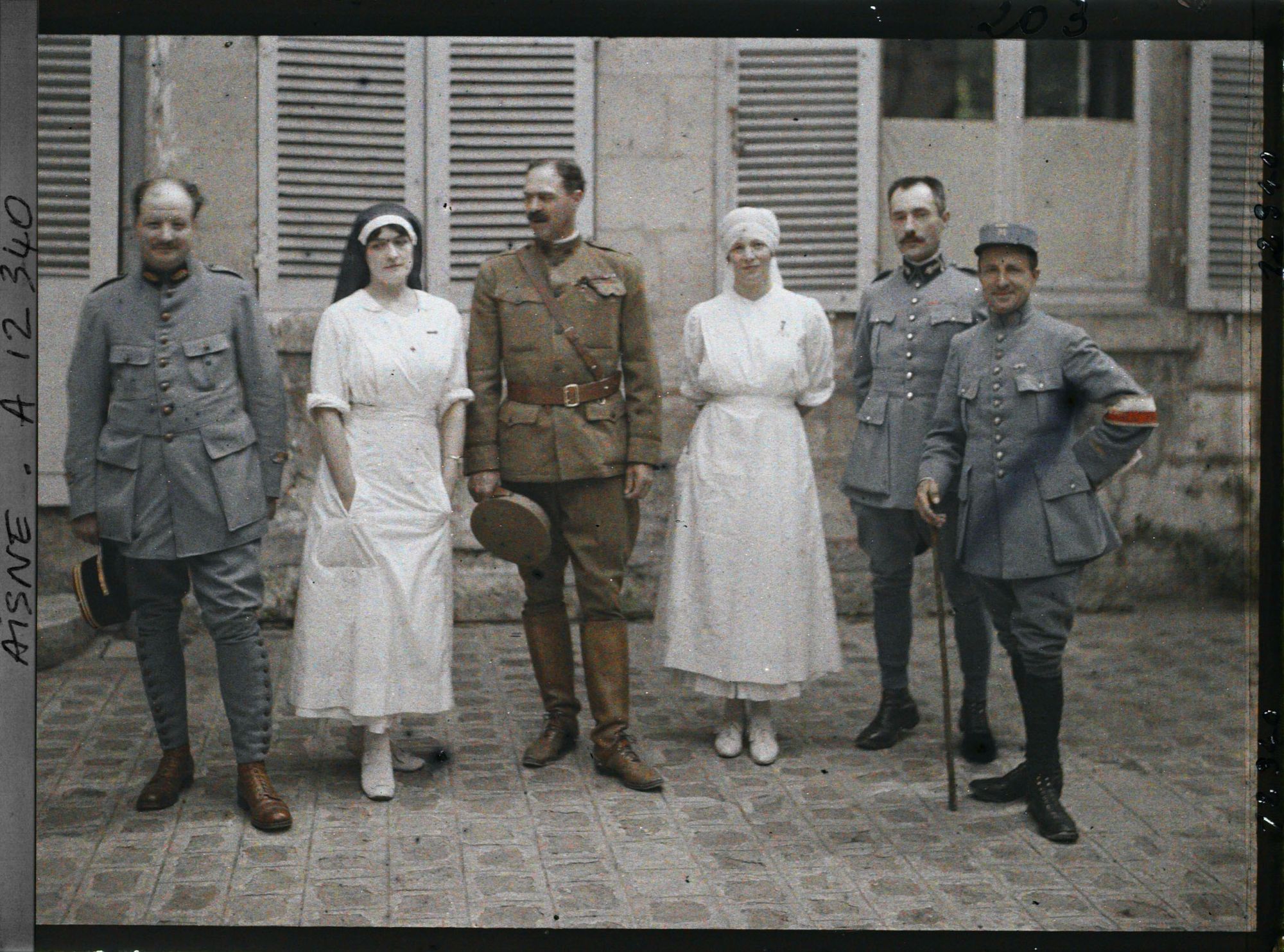 Image représentant Médecins français entourant un officier américain, Madame Mireille Andrieu coiffée d'un voile d'infirmière bleu et Rose Georgette Saint-Paul, infirmière major