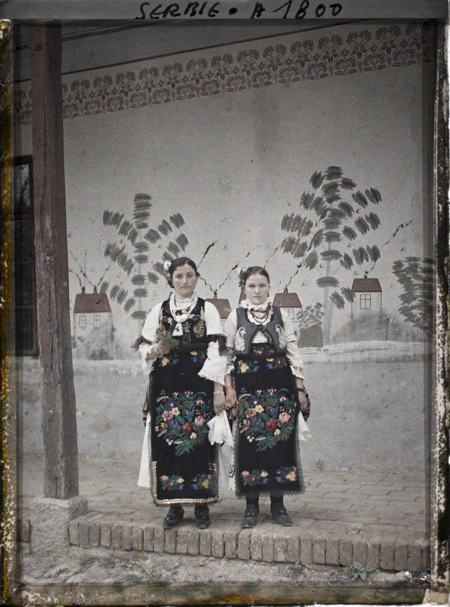 Image représentant Deux jeunes filles en costume traditionnel devant une maison sur la route d'Avala