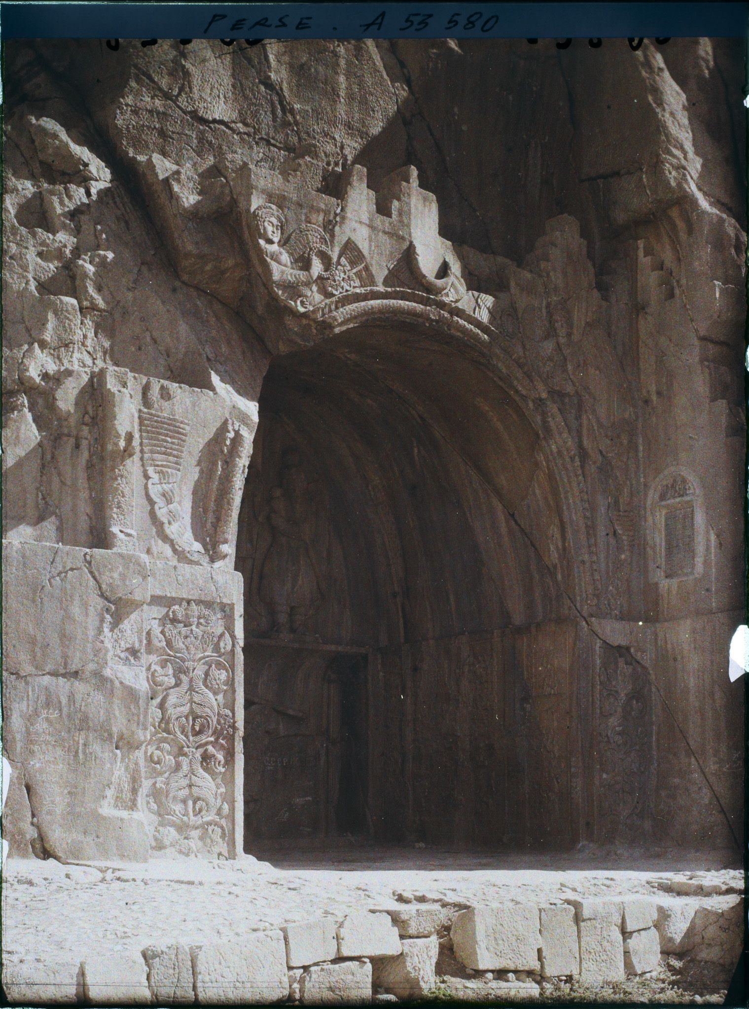 Image représentant La grande grotte, celle de Khosro II. Au-dessus de la voûte, figure ailée d'inspiration romaine portant l'anneau du pouvoir et le diadème royal