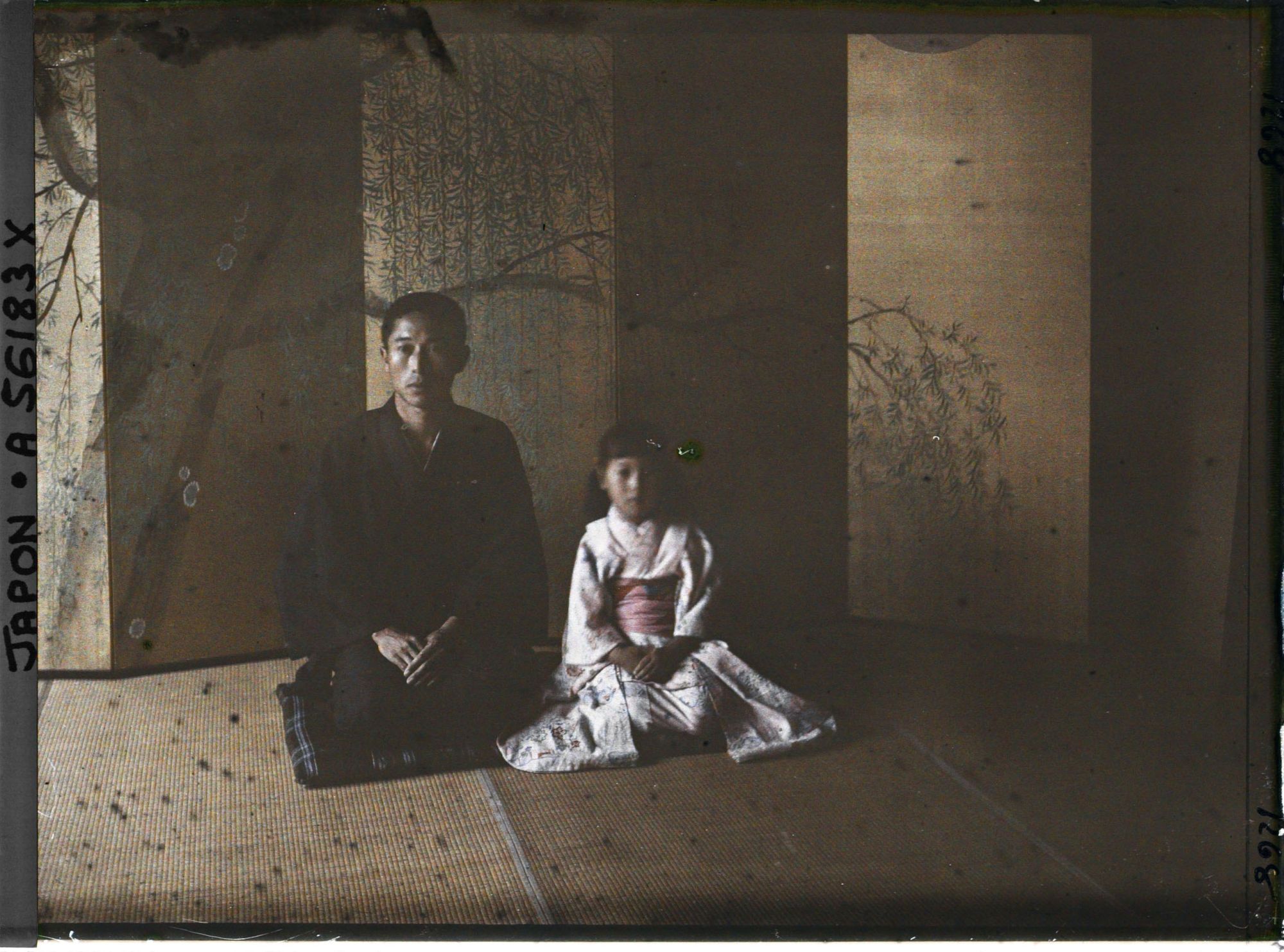 Image représentant Homme et fillette posant devant un paravent de cérémonie