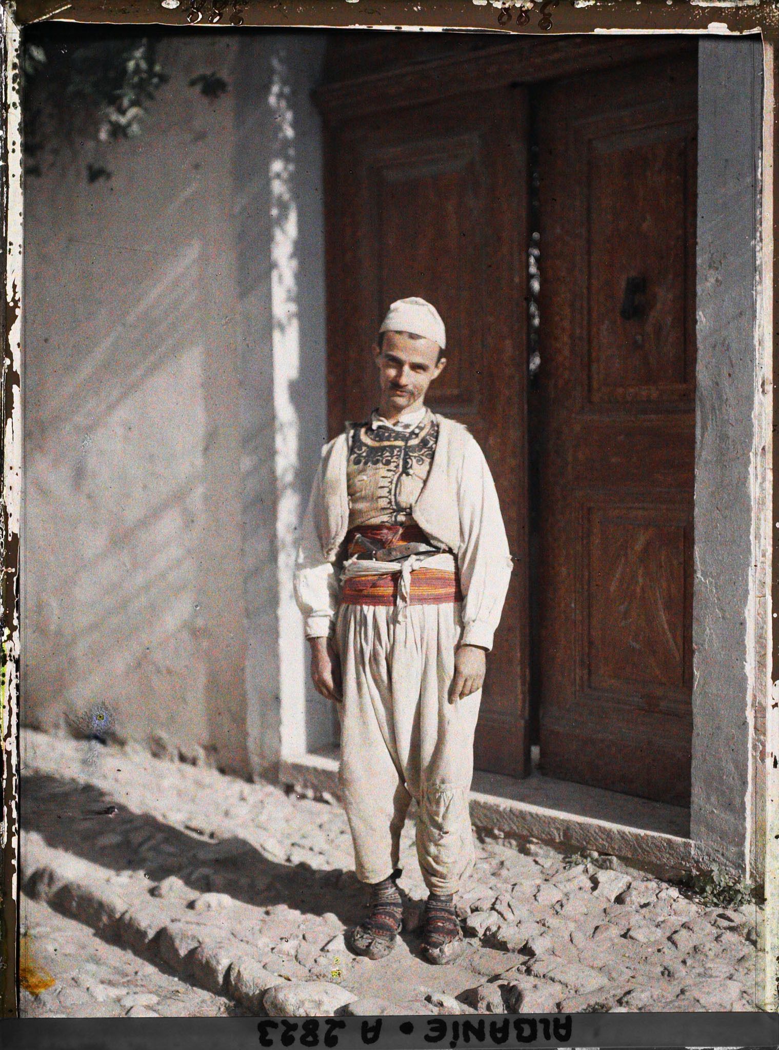 Image représentant Un Albanais de Berat devant une porte marron