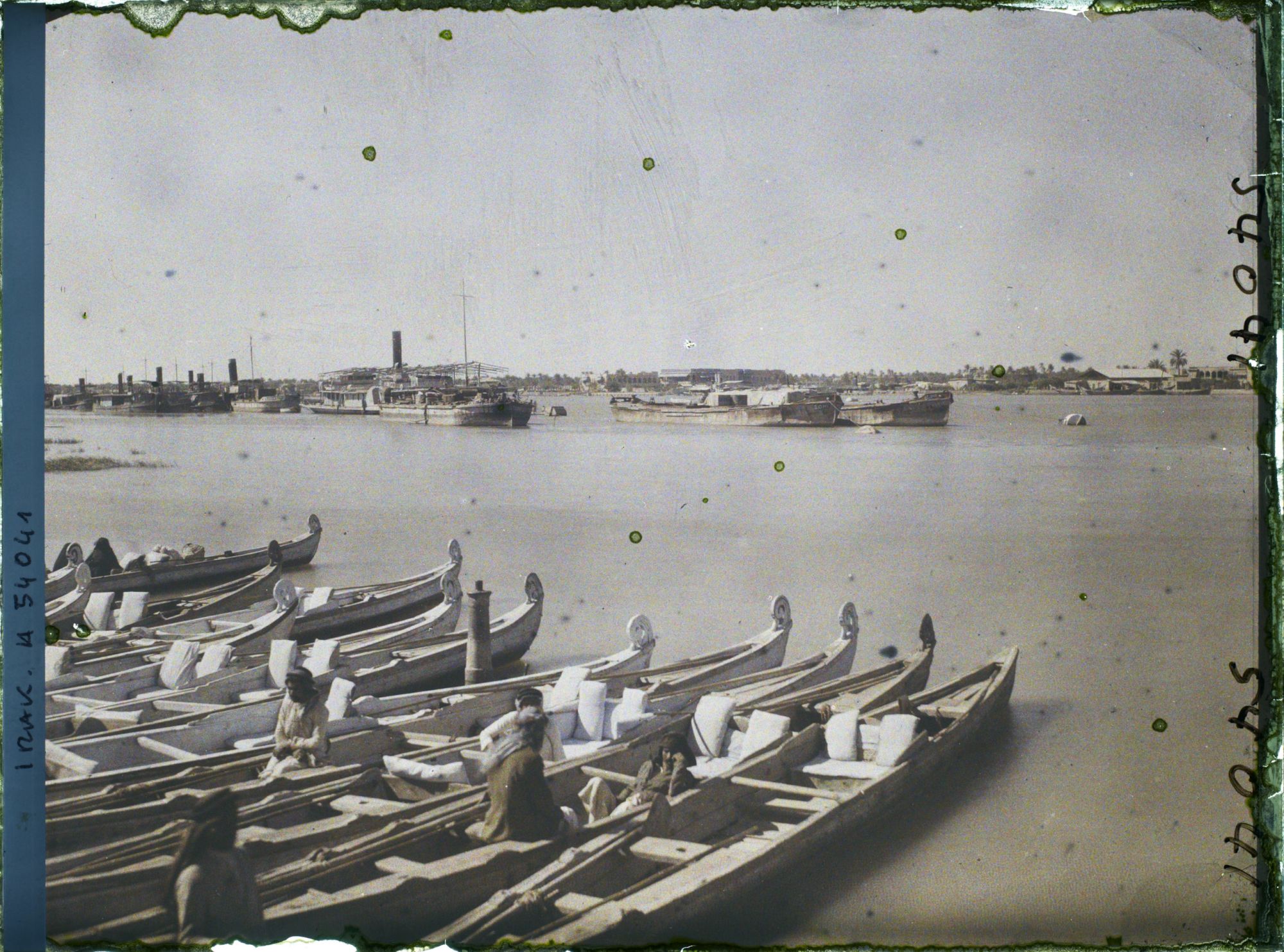 Image représentant La ville, vue sur la rive gauche du Chatt al 'Arab ; au premier plan, des bateaux "Belems"