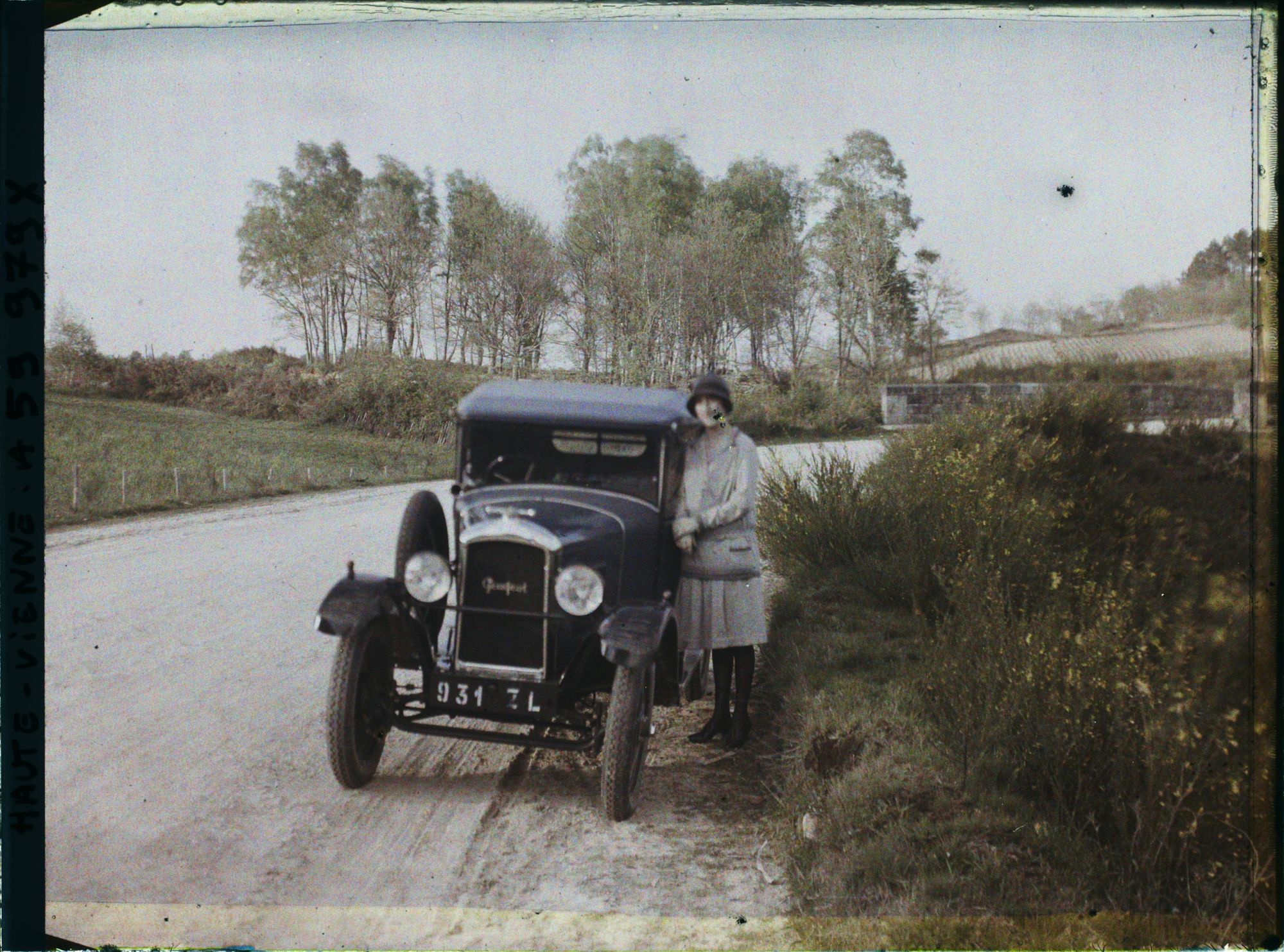 Image représentant Madame Misme pose à côté de sa voiture, un modèle Peugeot type 190 torpedo, sur la route de Jumilhac