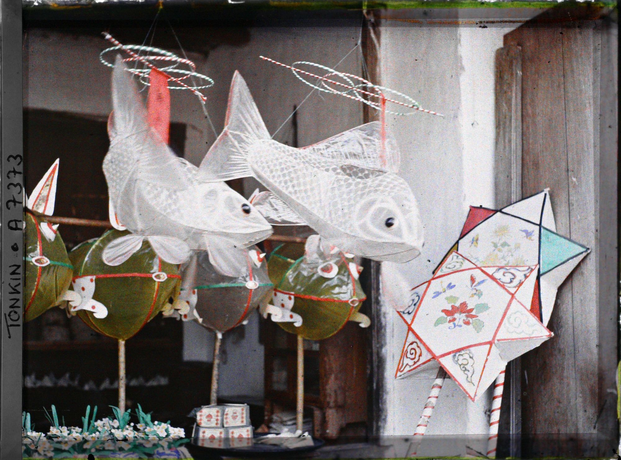 Image représentant Un étalage de jouets en papier huilé devant une boutique, dans la " rue du Chanvre "