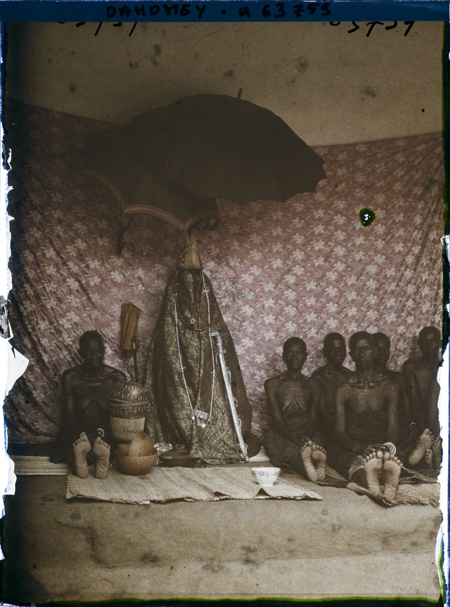 Image représentant Sacrifice à la tête : femmes du roi Houdji entourant les insignes de la royauté à l'occasion de la séparation du crâne du roi défunt de son corps