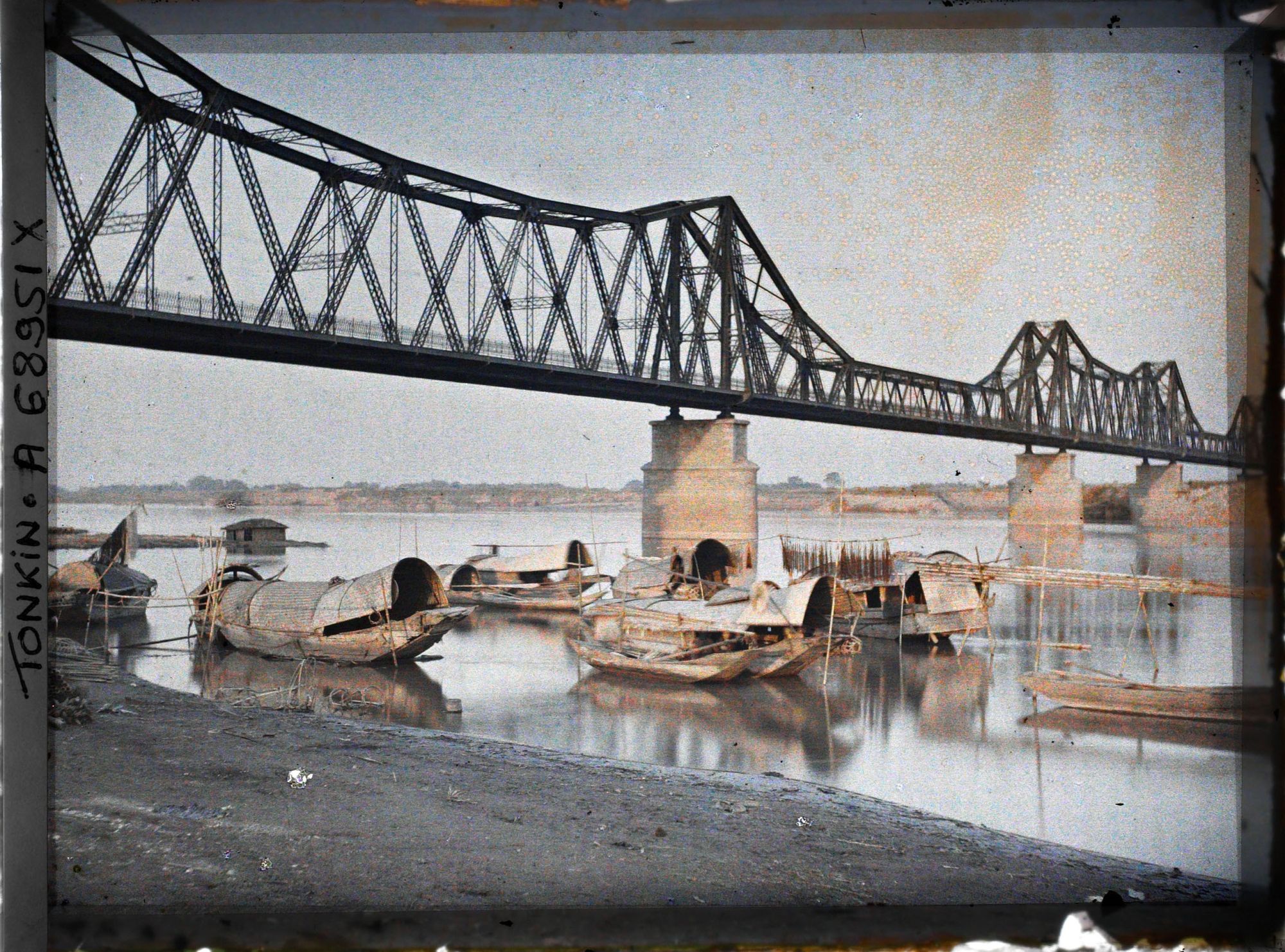 Image représentant Le pont Doumer et les sampans bordant les quais du Fleuve Rouge, le matin