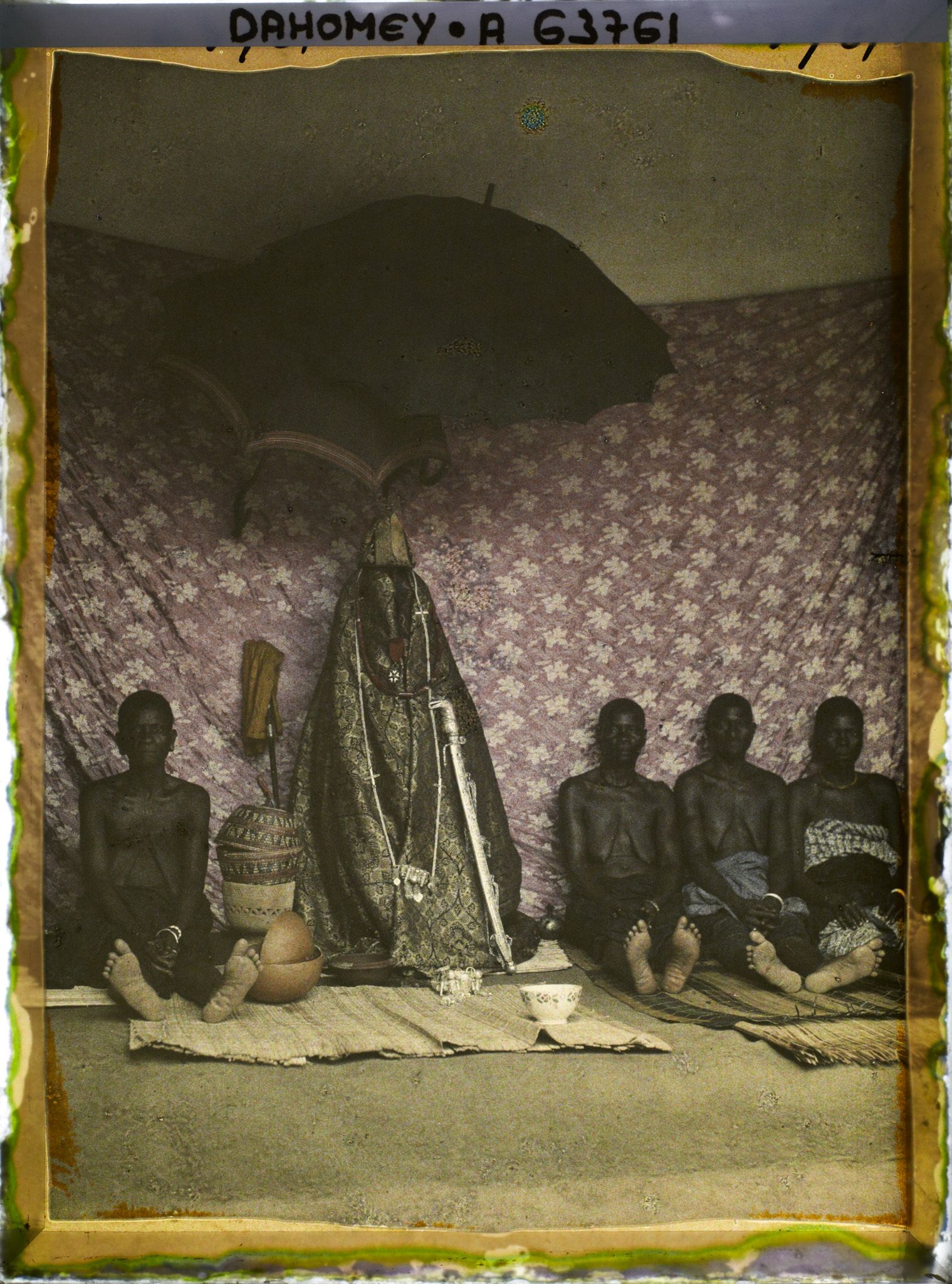 Image représentant Sacrifice à la tête : femmes du roi Houdji entourant les insignes de la royauté à l'occasion de la séparation du crâne du roi défunt de son corps