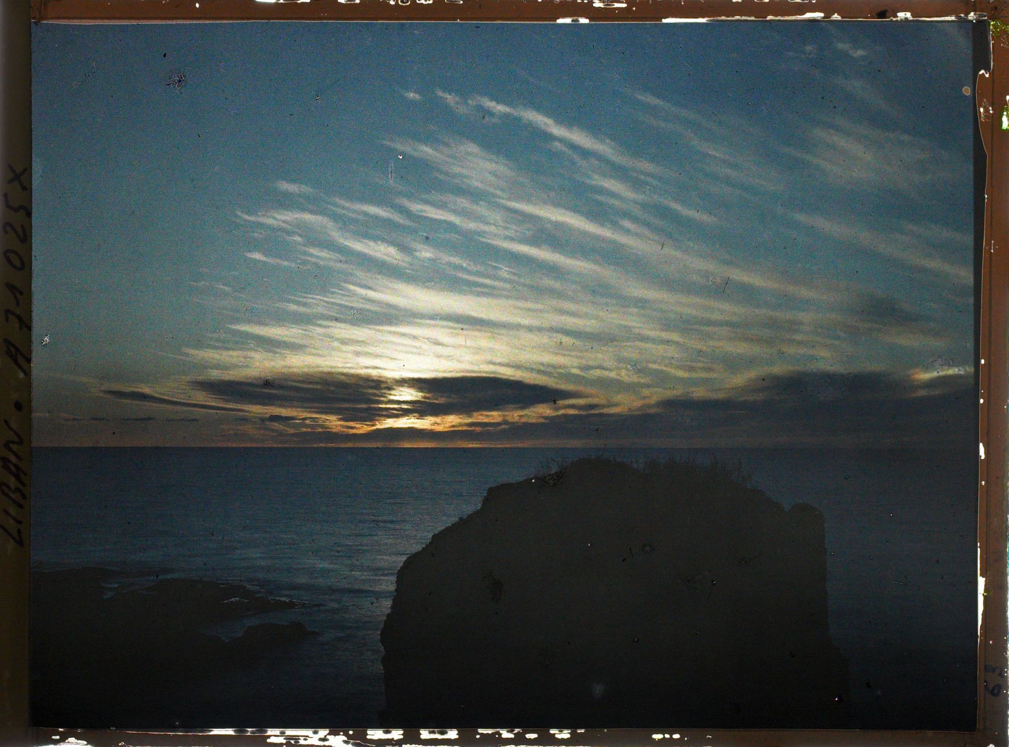 Image représentant Coucher de soleil sur la mer. Au premier plan, des rochers face aux Grottes aux Pigeons