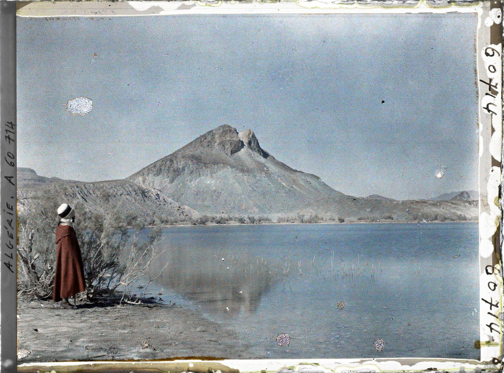 Image représentant Un homme se tient sur la rive du lac ; à l'arrière-plan, les pitons de marne verte