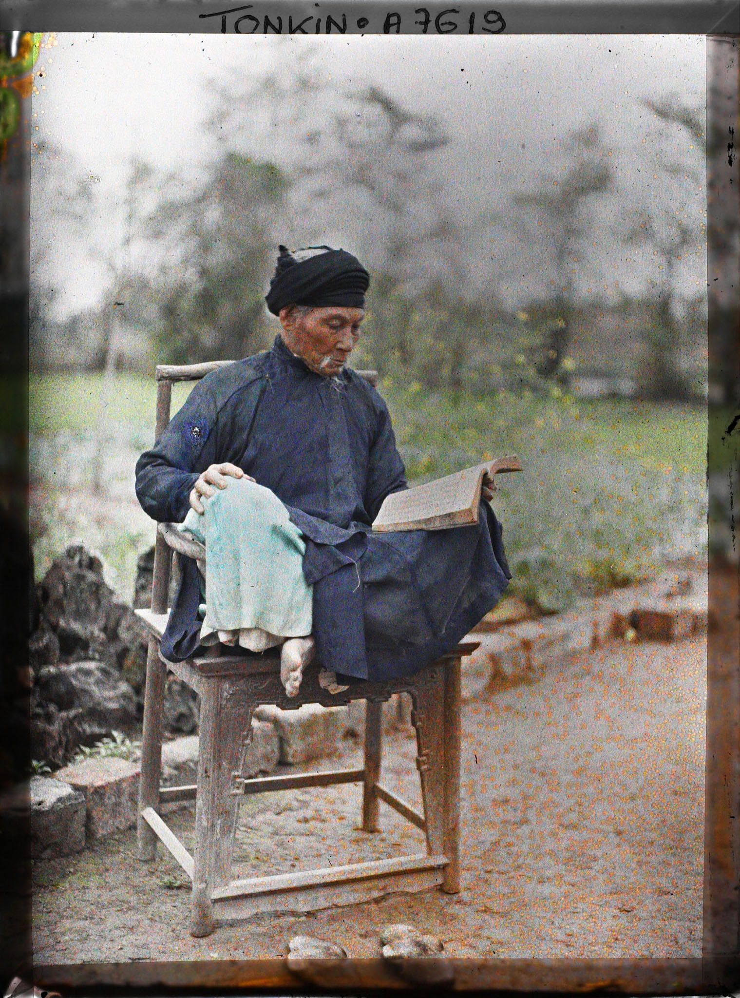 Image représentant Un lettré lisant, assis en tailleur dans un fauteuil en bois