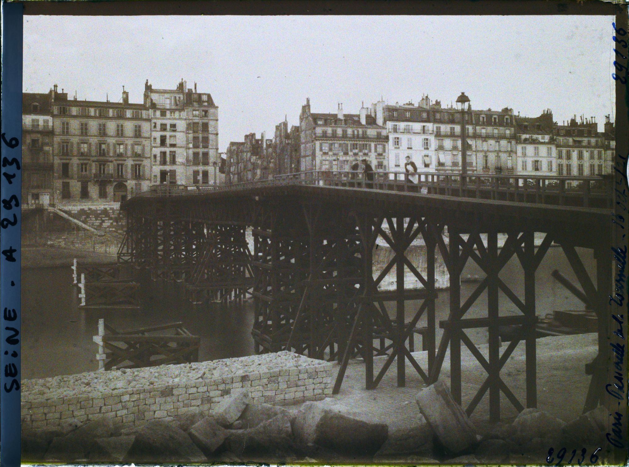 Image représentant La passerelle en bois remplaçant provisoirement le pont de la Tournelle en reconstruction, vue depuis le quai de la Tournelle vers les quais d'Orléans et de Béthune