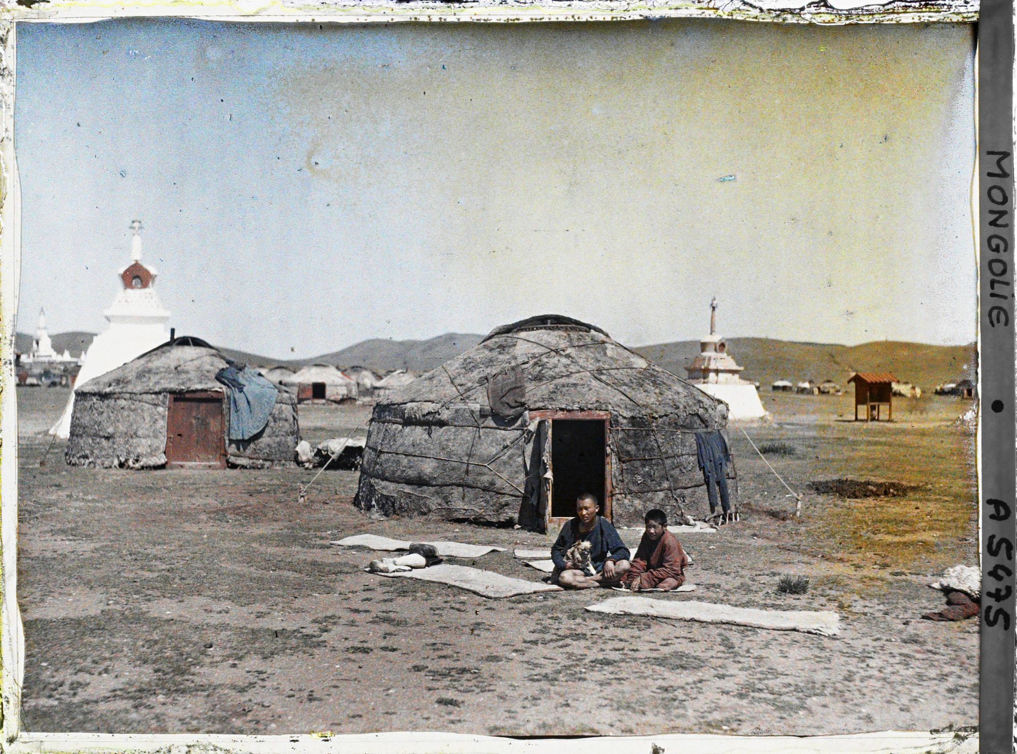 Image représentant Deux jeunes Mongols assis devant une yourte