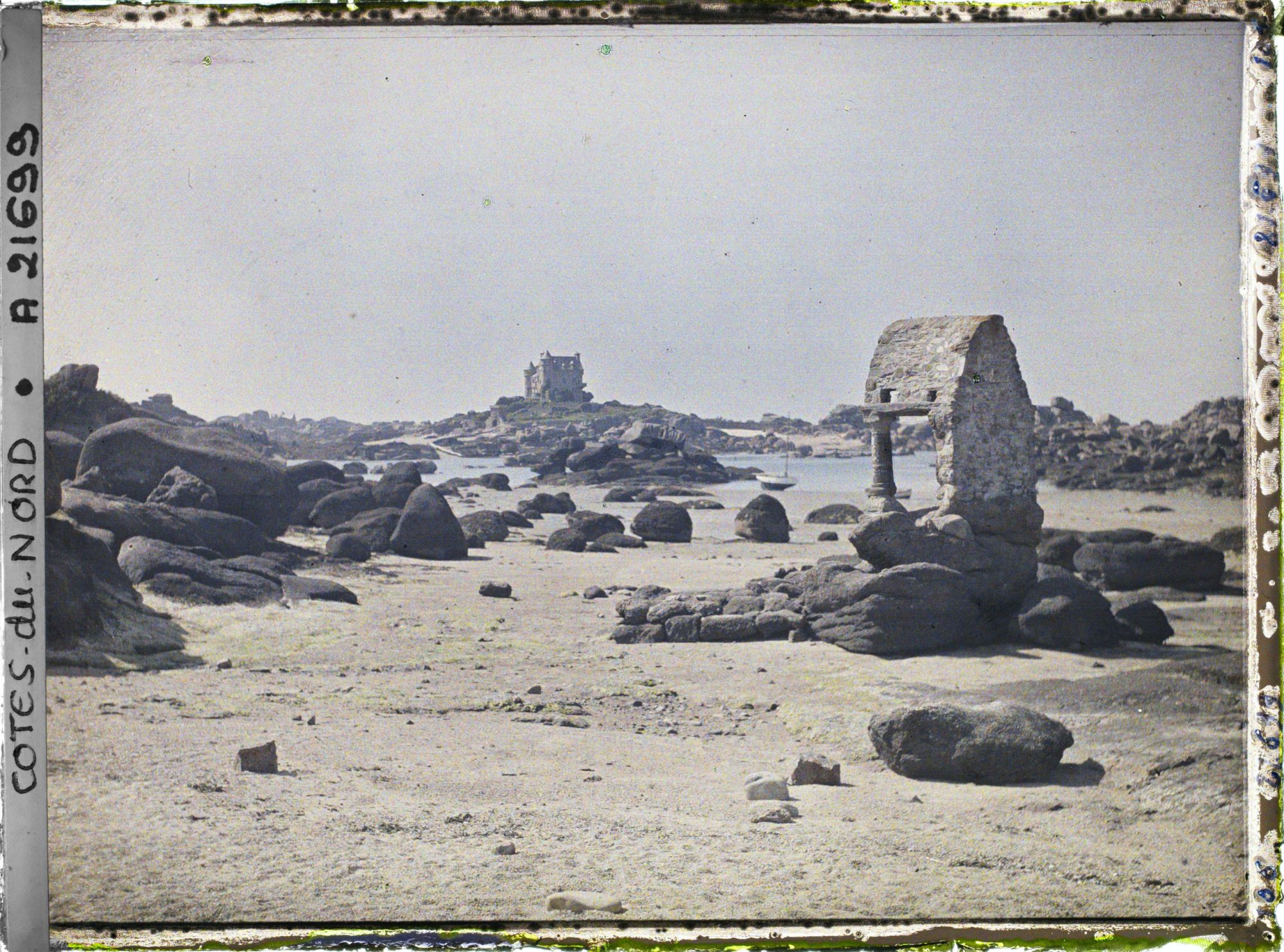 Image représentant L'oratoire de Saint-Guirec à marée basse ; à l'arrière-plan, le château de Costaéres