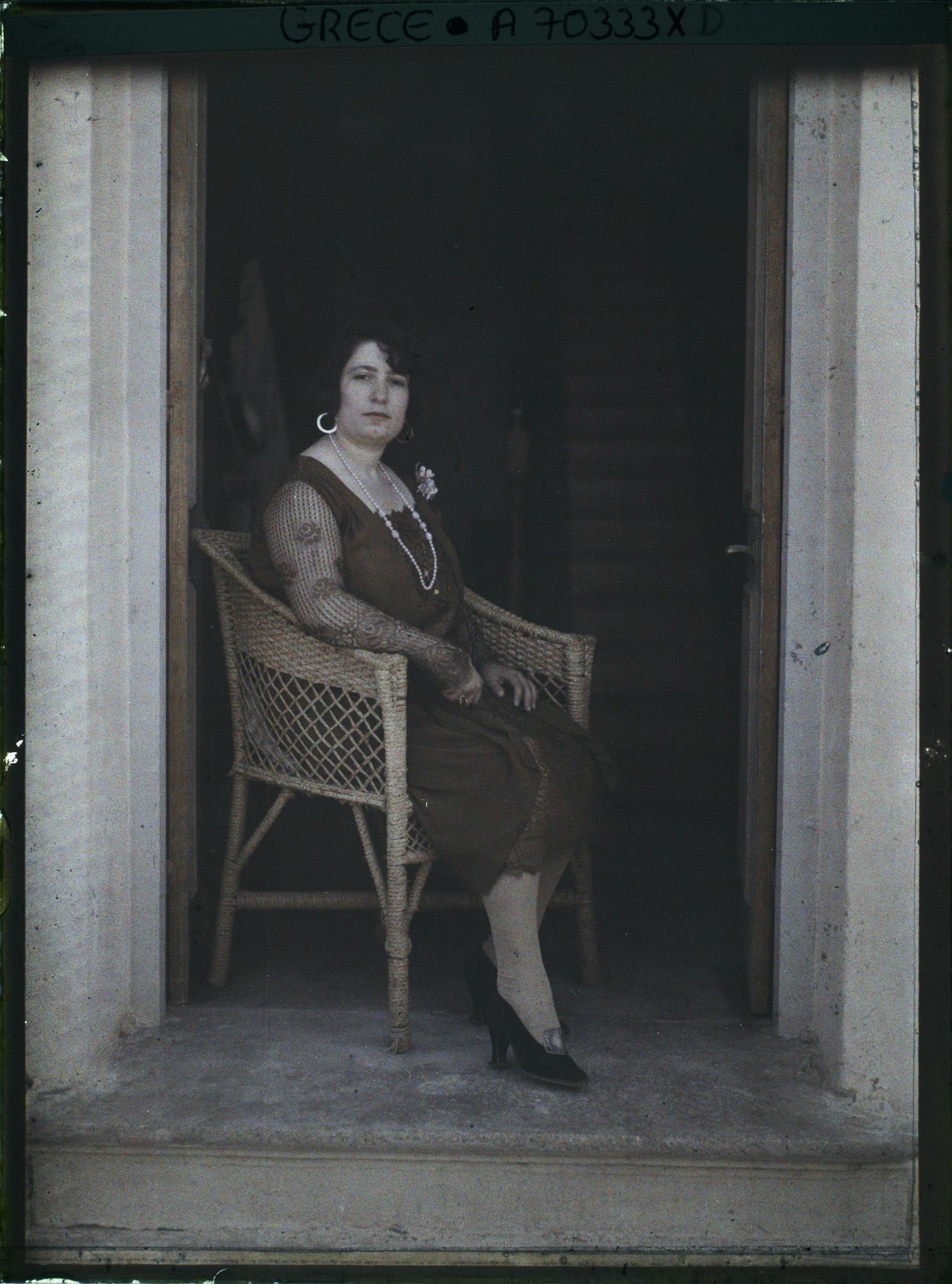 Image représentant Femme d'une quarantaine d'années élégamment vêtue, assise sur seuil d'une maison ou d'un hôtel (guide, interprète, compagne de l'opérateur ?)