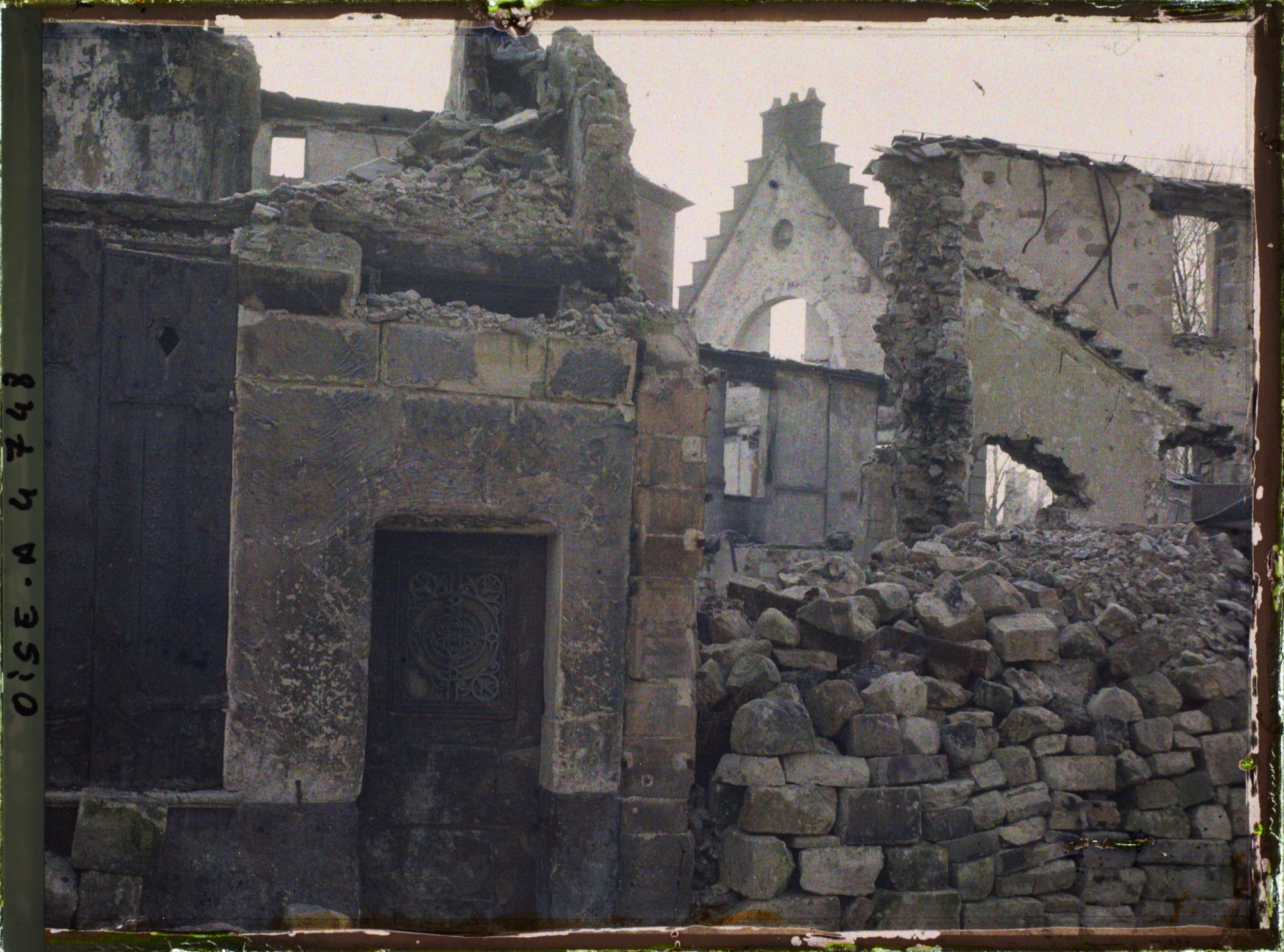 Image représentant En face du magasin Ygouf, ruines avec une porte peinte brûlée, au 1er plan