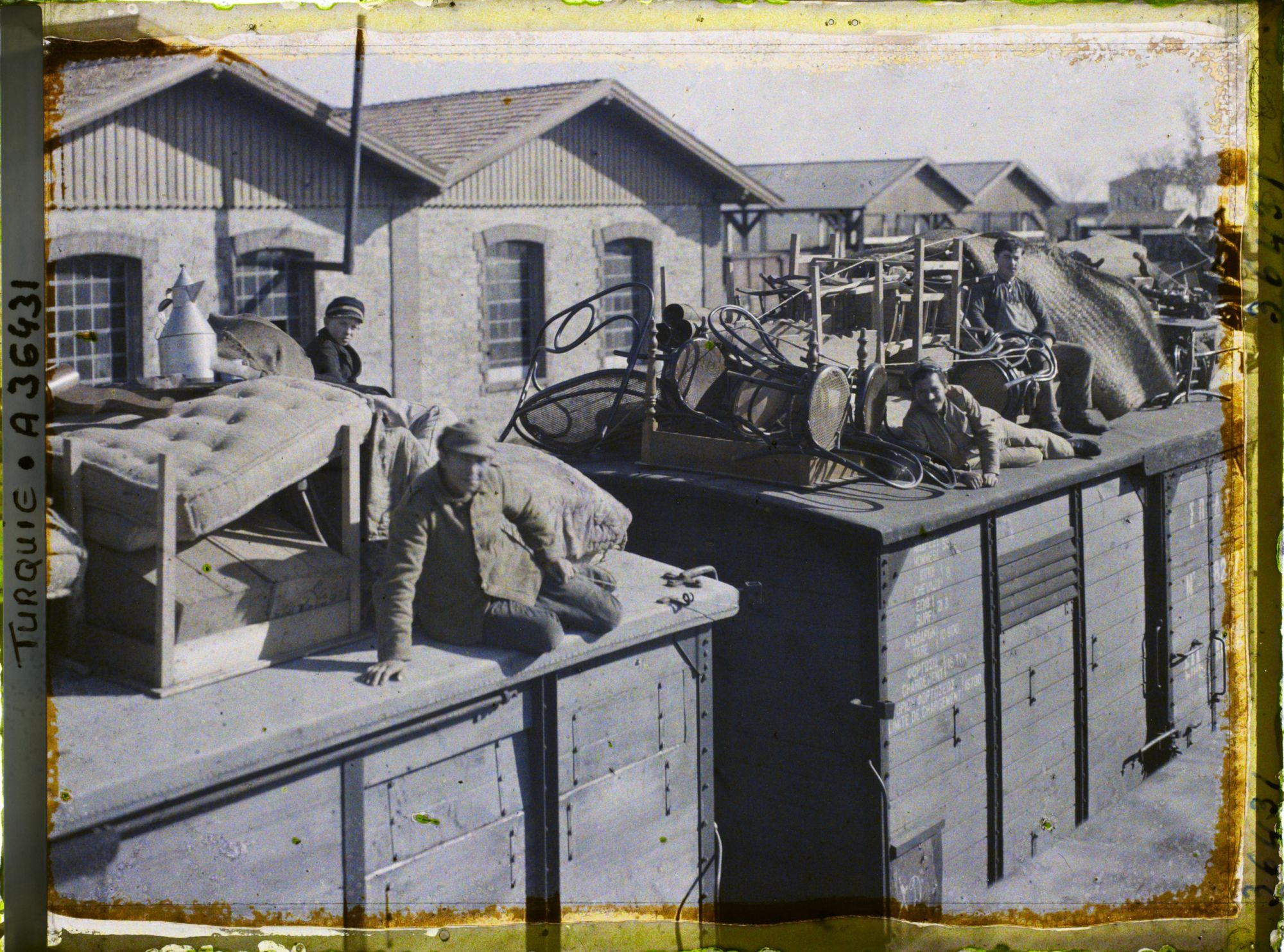 Image représentant Grecs quittant la ville sur le toit d'un train chargé de mobilier, de matellas et d'objets divers