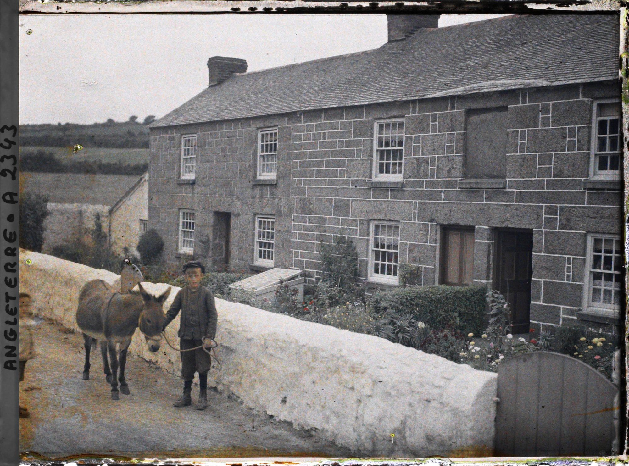 Image représentant Un enfant et un âne près d'une maison