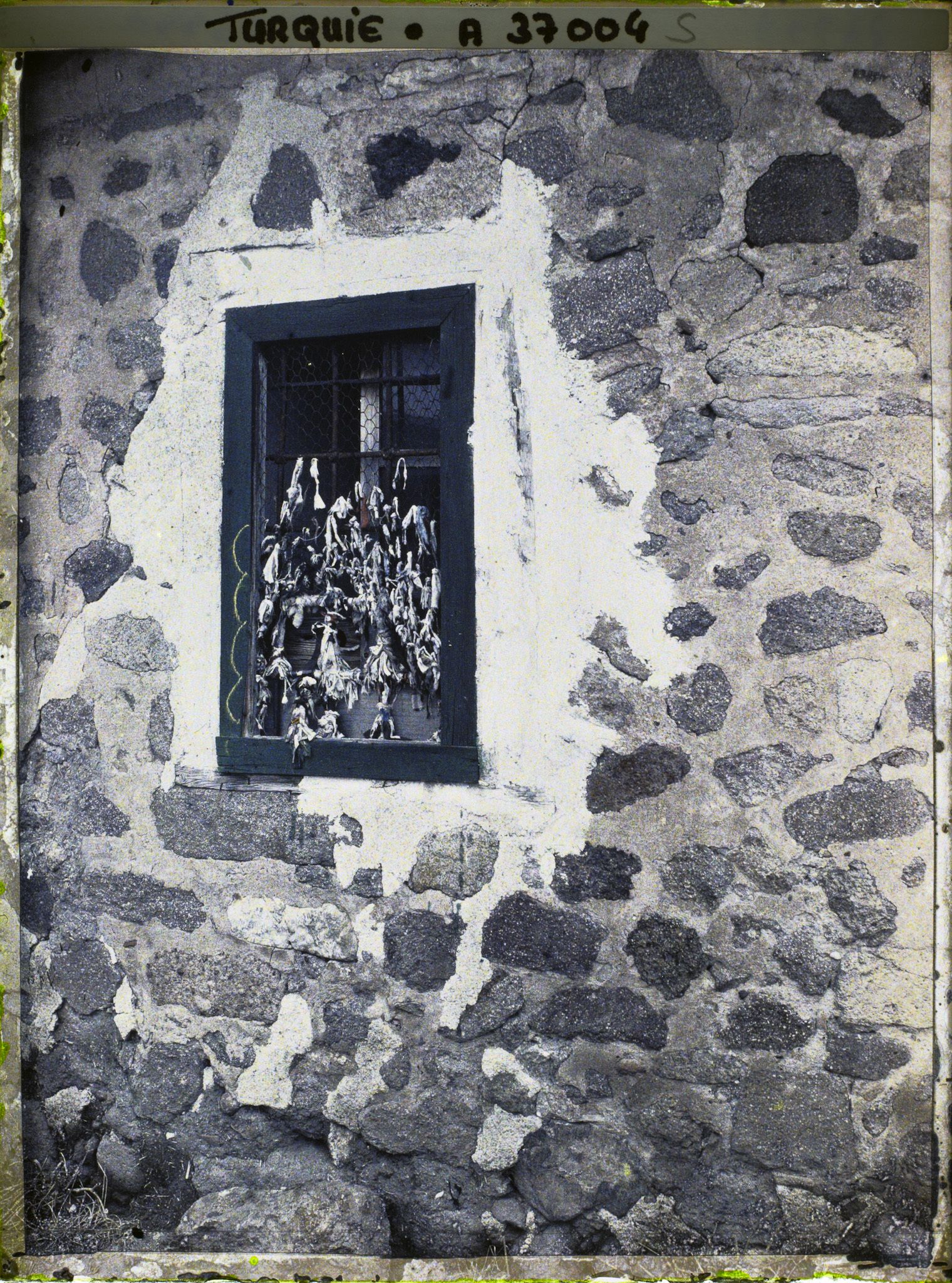 Image représentant La fenêtre d'un mausolée moderne pour un saint personnage, ornée de petits bouts de chiffon en guise d'ex-voto