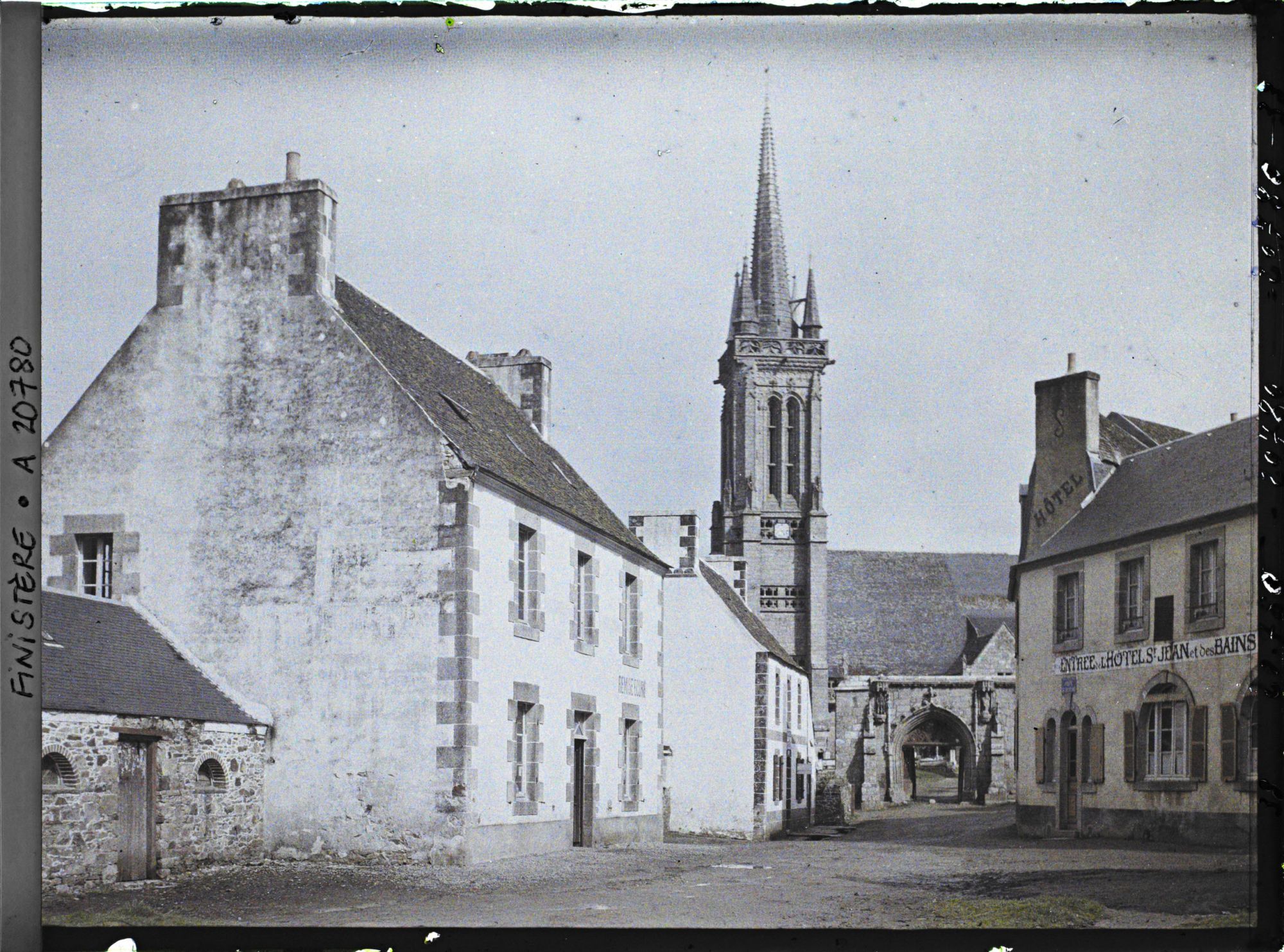 Image représentant Une place du village et l'église Saint-Jean-du-Doigt derrière la porte monumentale du cimetière