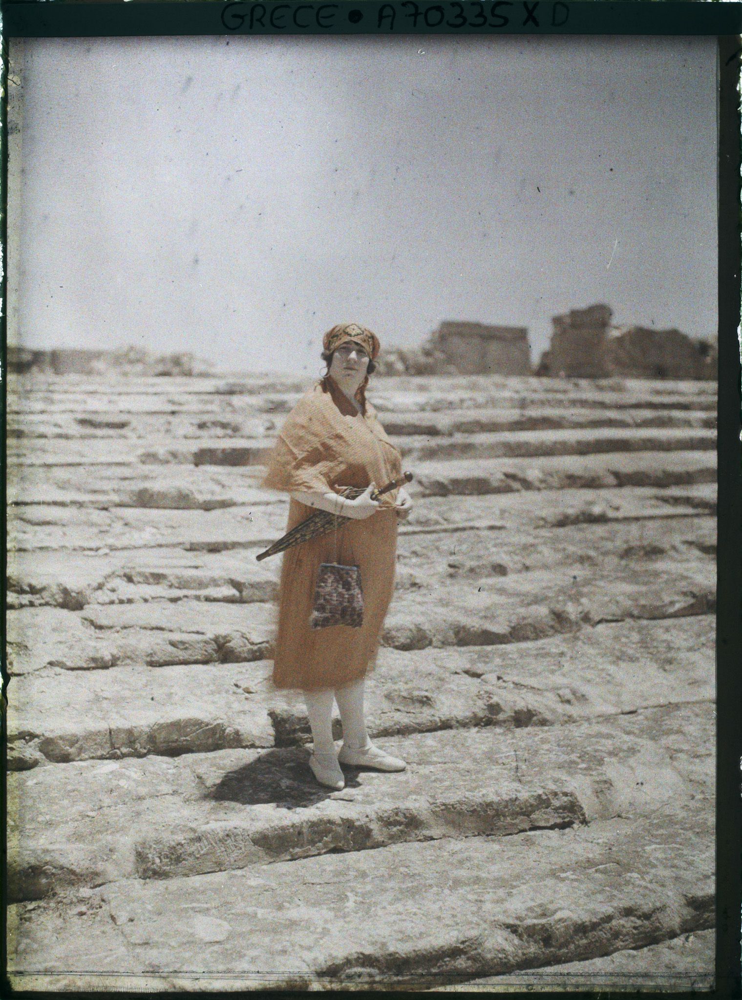 Image représentant Femme d'une quarantaine d'années élégamment vêtue, sur les marches d'un site archéologique (guide, interprète, compagne de l'opérateur ?)