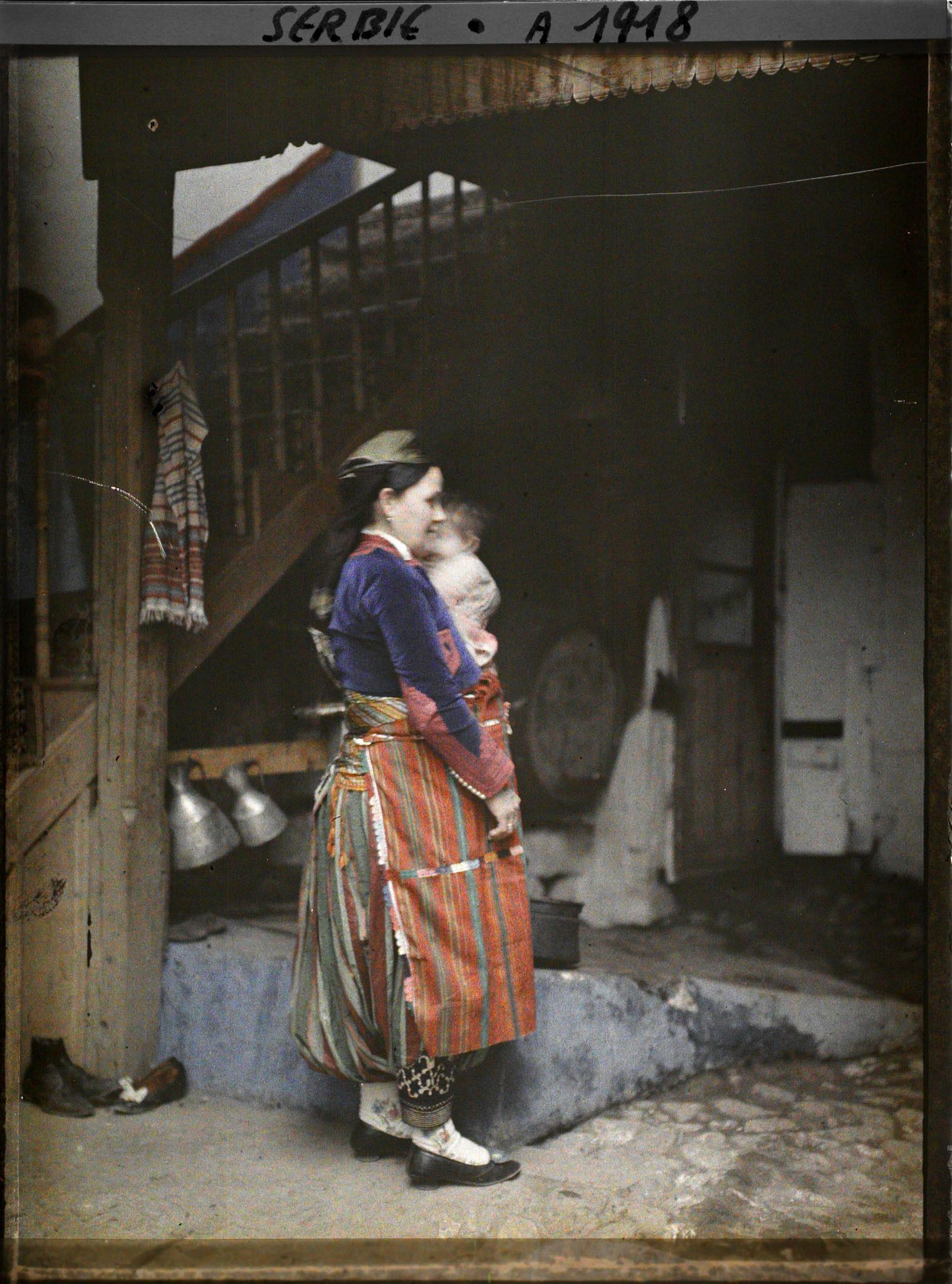 Image représentant Une Serbe en costume traditionnel dans la cour d'une maison