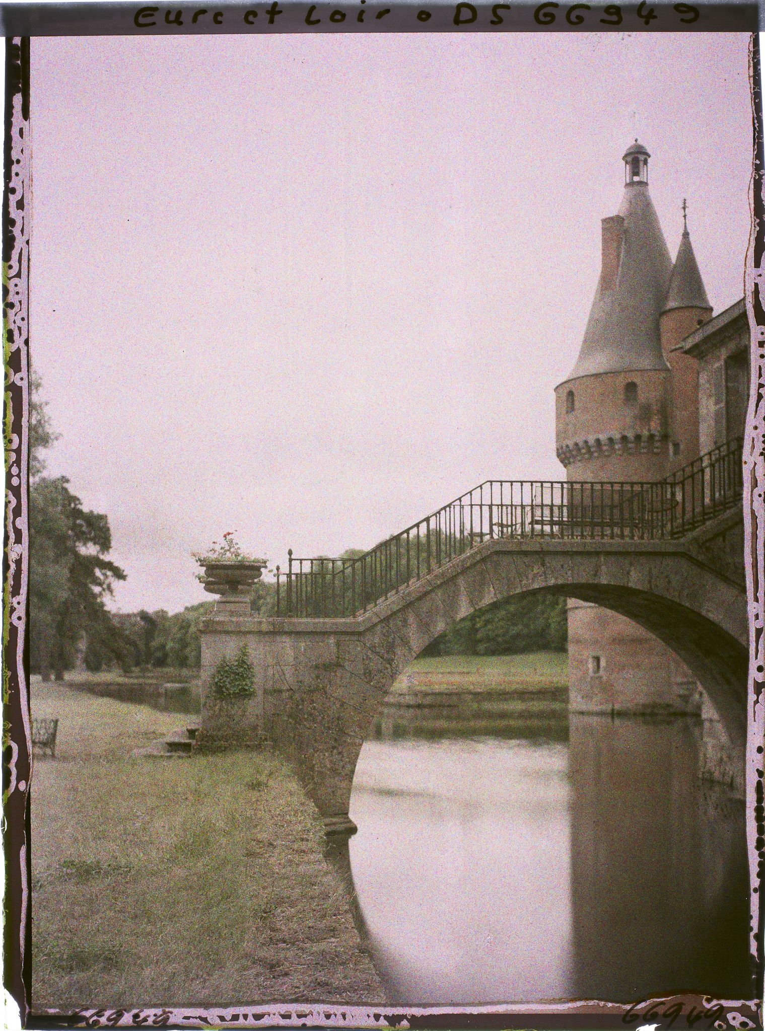 Image représentant Le pont de pierre au-dessus des douves du château et la tour de brique avec toiture en poivrière