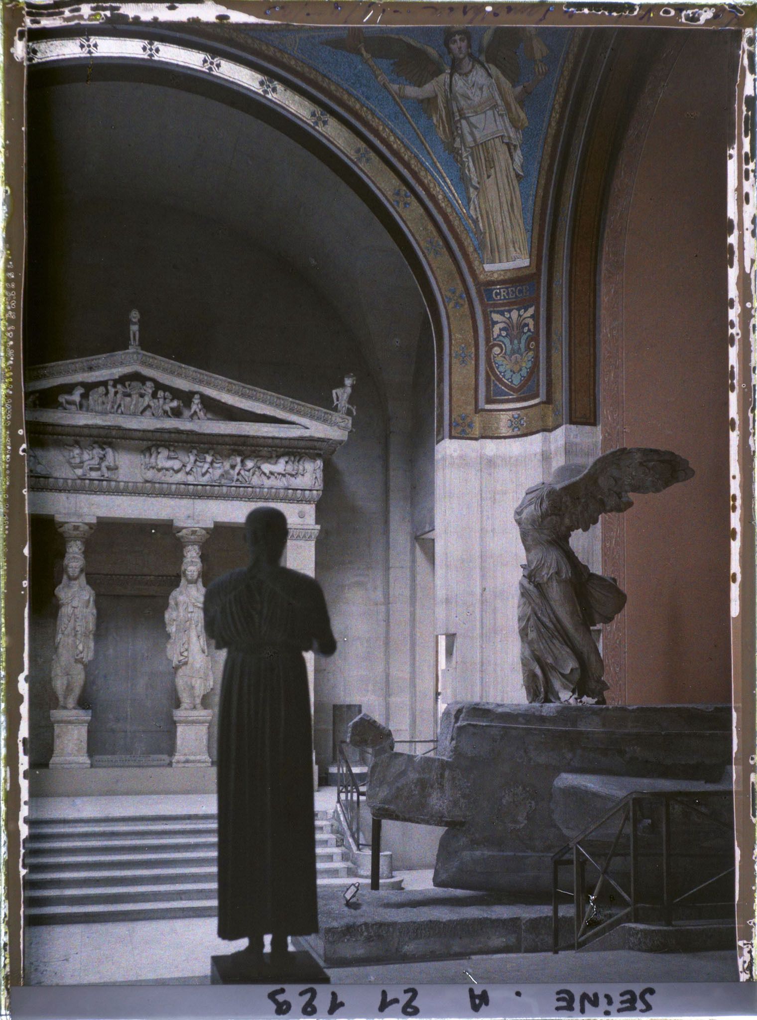Image représentant La Victoire de Samothrace sur le dernier palier de l'escalier Daru et une copie en fonte de l'Aurige de Delphes, musée du Louvre