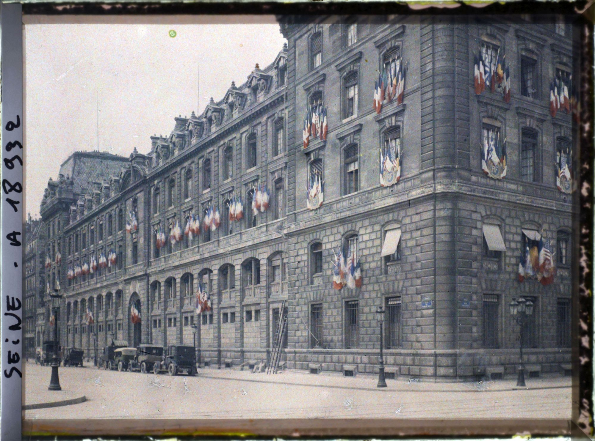Image représentant La préfecture de police à l'angle de la rue de la Cité et du quai du marché neuf, décorée de drapeaux pour les fêtes de la Victoire des 13 et 14 juillet 1919