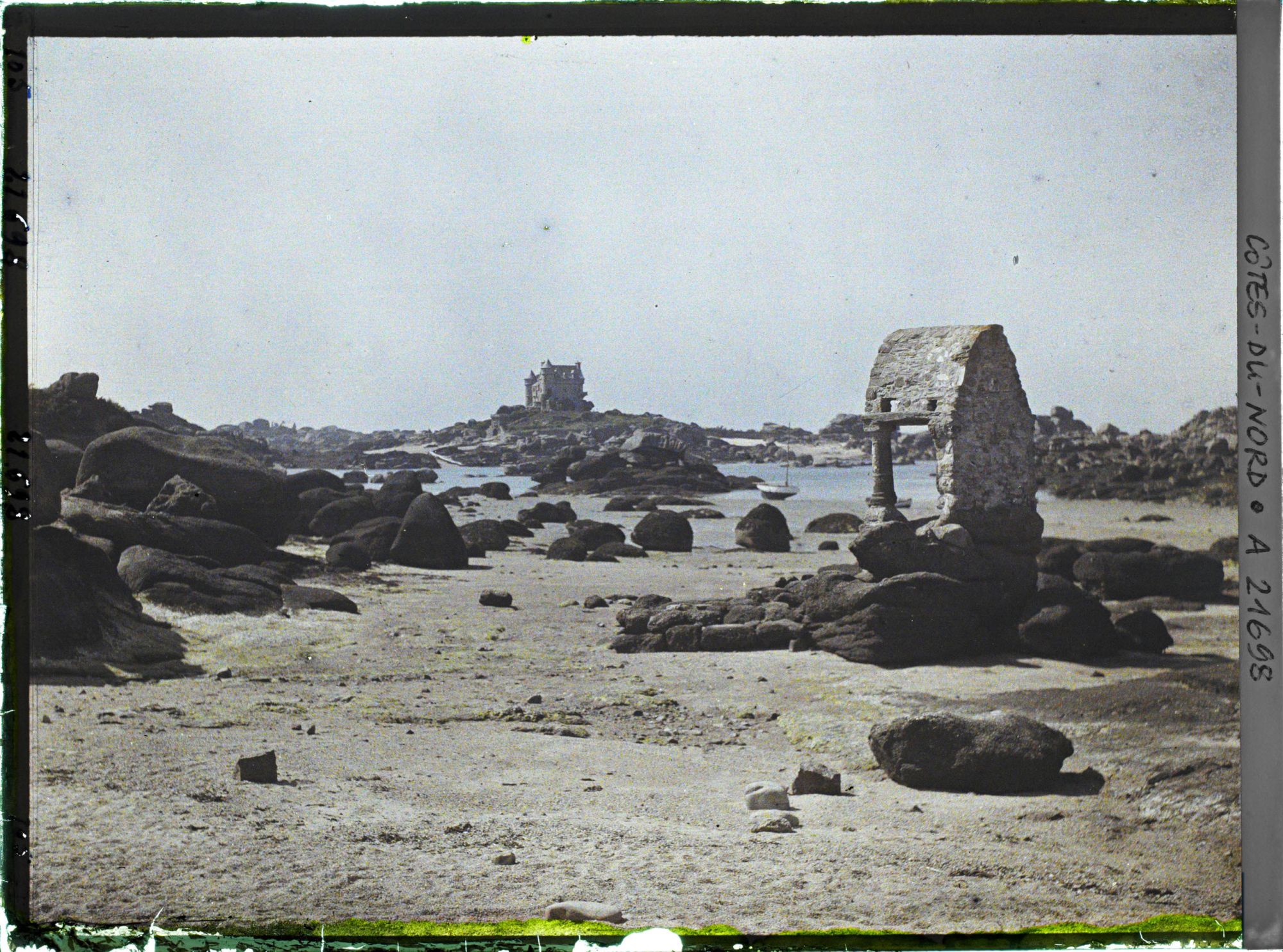 Image représentant L'oratoire de Saint-Guirec à marée basse ; à l'arrière-plan, le château de Costaéres
