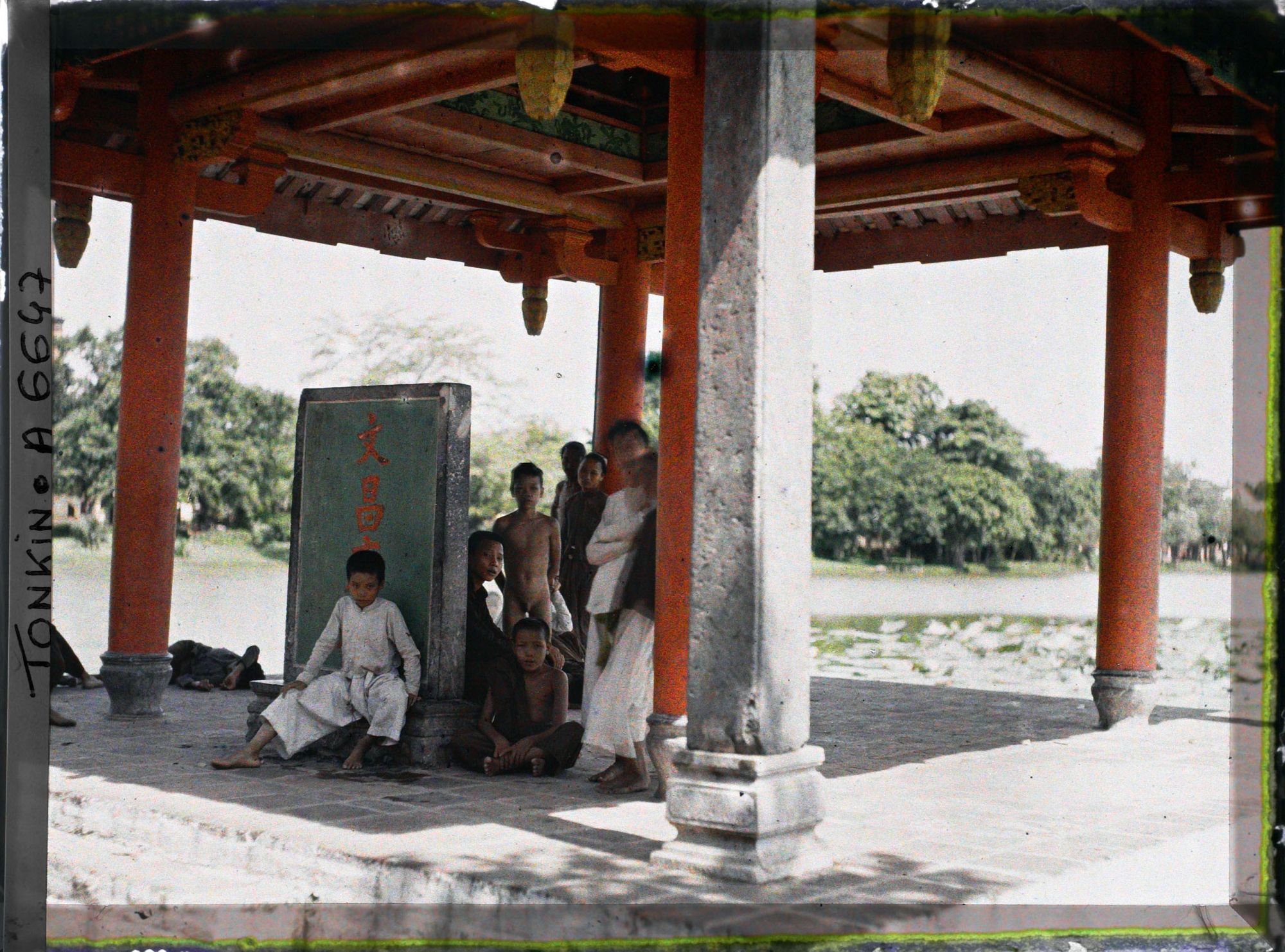 Image représentant Un groupe d'enfants sous le Thui-toa " Kiosque du bord de l'eau ", abritant une stèle de pierre nommée " Tablette du Temple de Van-xu'o'ng "